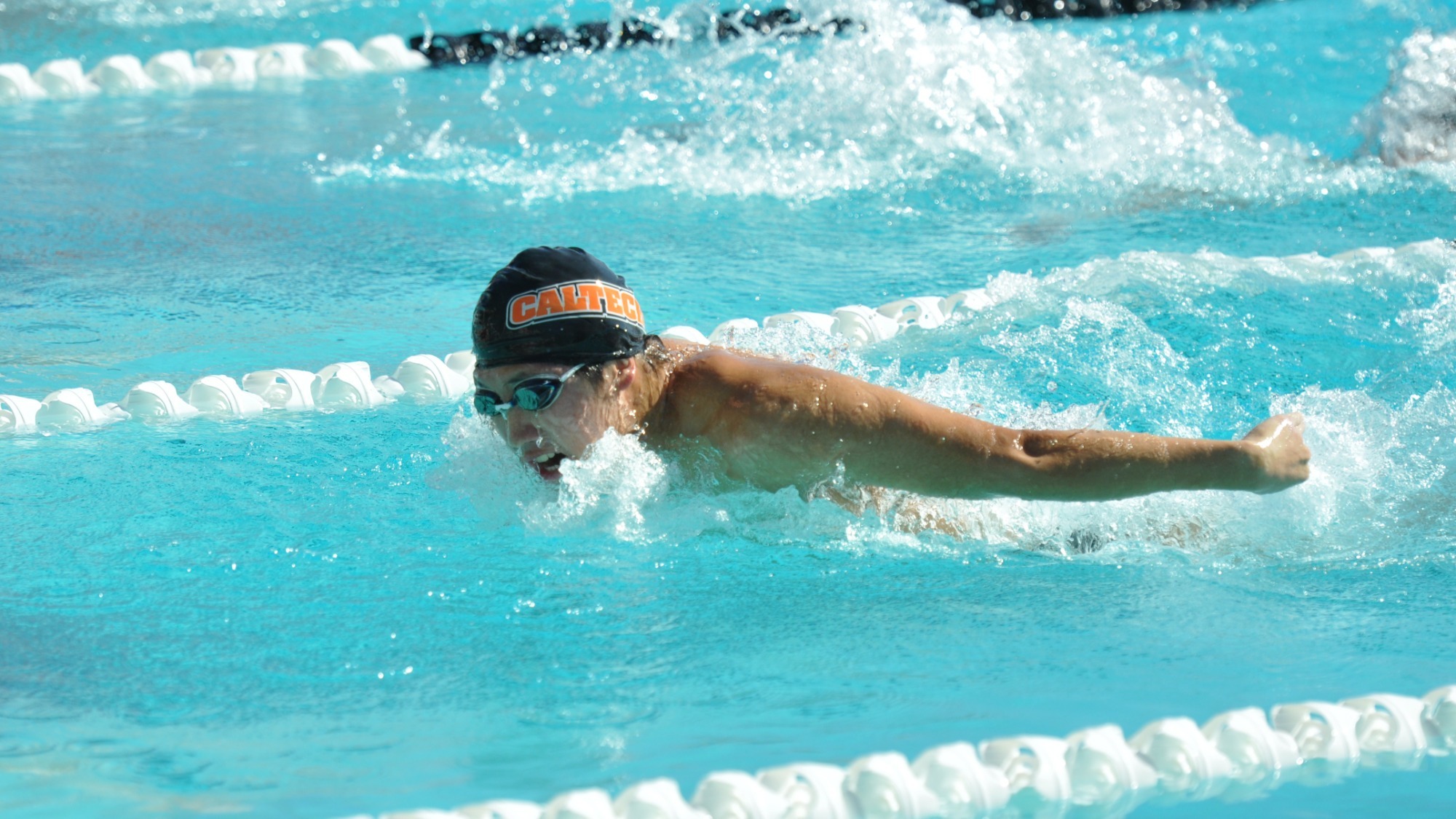 Nicholas Bai inhales with his mouth just above the water and his arms stretched behind him in the middle of his butterfly stroketterfly