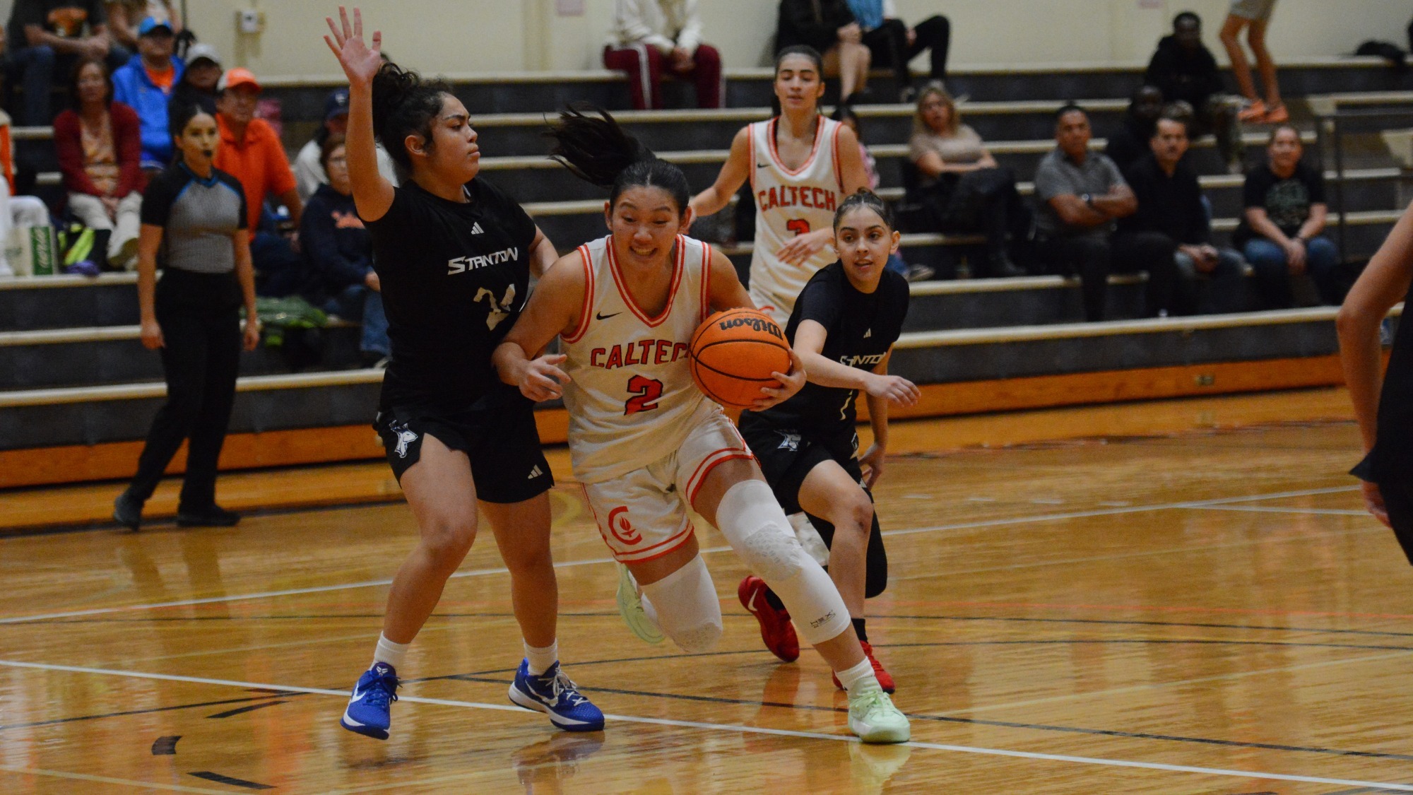 Kyra Phaychanpheng drives towards the basket, cradling the ball in her left hand and fighting off a defender with her right