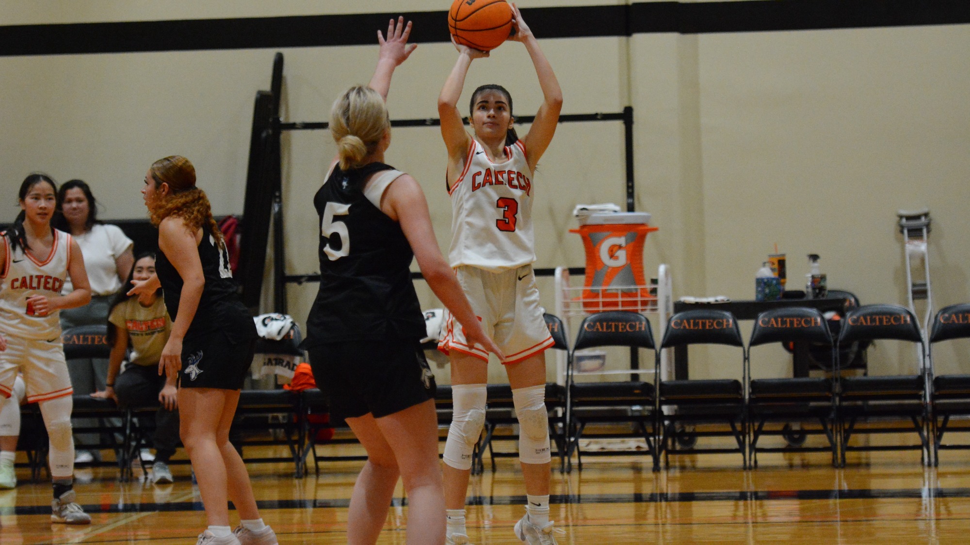 Zeynep Goktepe faces the camera as she holds the ball above her head as part of a shooting motion from the perimeter wing. She is defended by a player in a black jersey with the number 