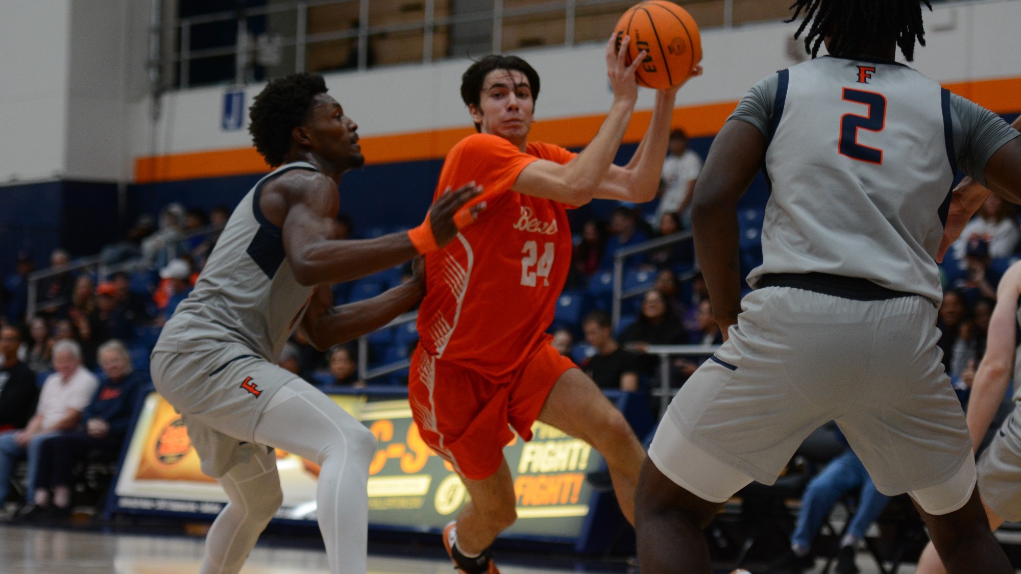Dorian Glogovac protects the ball with both hands as he drives between two defenders in a game against Cal State Fullerton