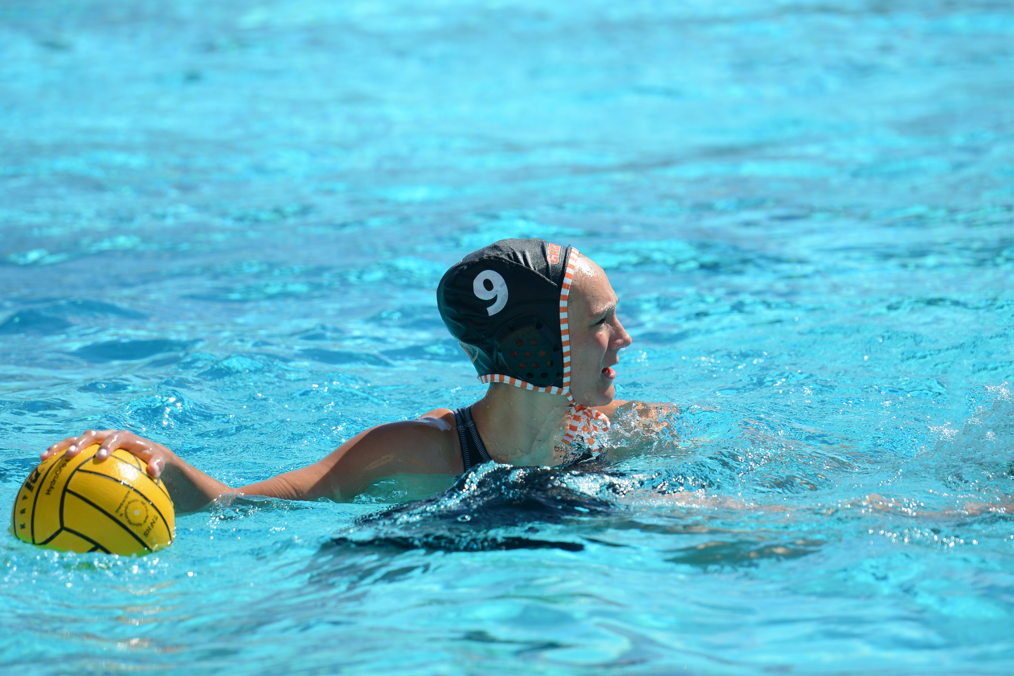 Emma Titus carrying the ball up the pool and enthusiastically communicating to her teammates which are off screen