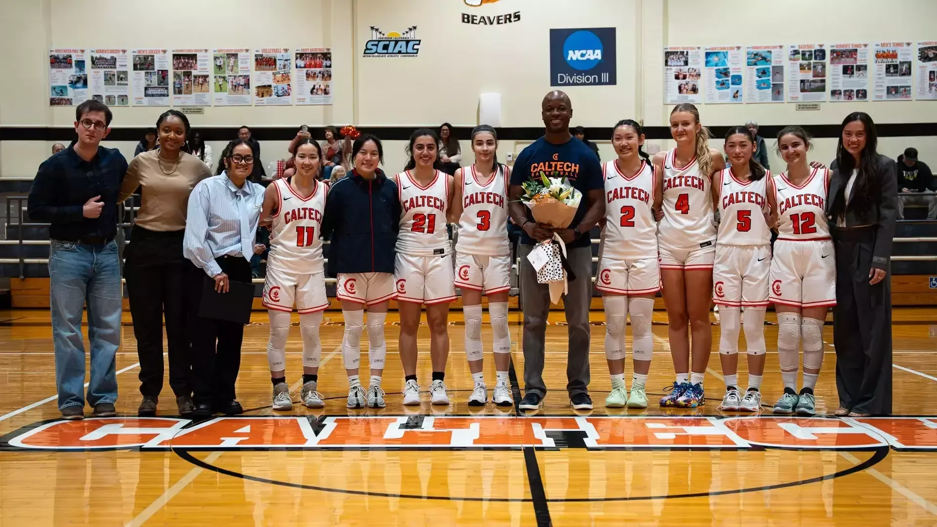 John Dabiri joins the Women's Basketball team at mid-court for a team photo