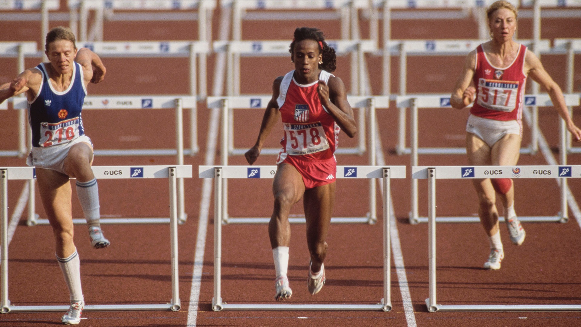 #578 Jackie Joyner-Kersee of the United States clears the hurdle ahead of #276 Sabine John of East Germany and #517 Natalya Shubenkova of the Soviet Union