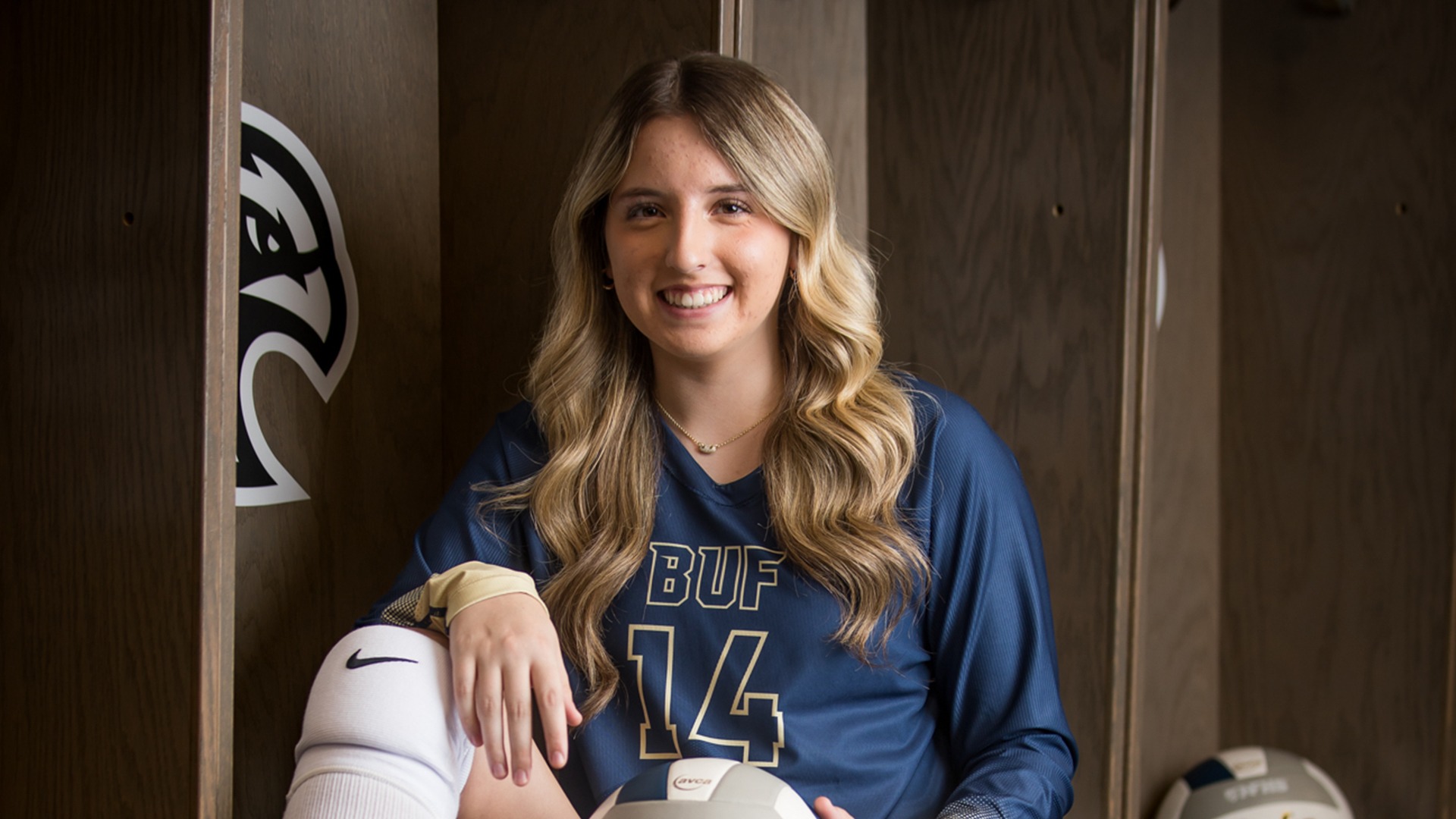 Picture of a girl holding a volleyball and smiling.