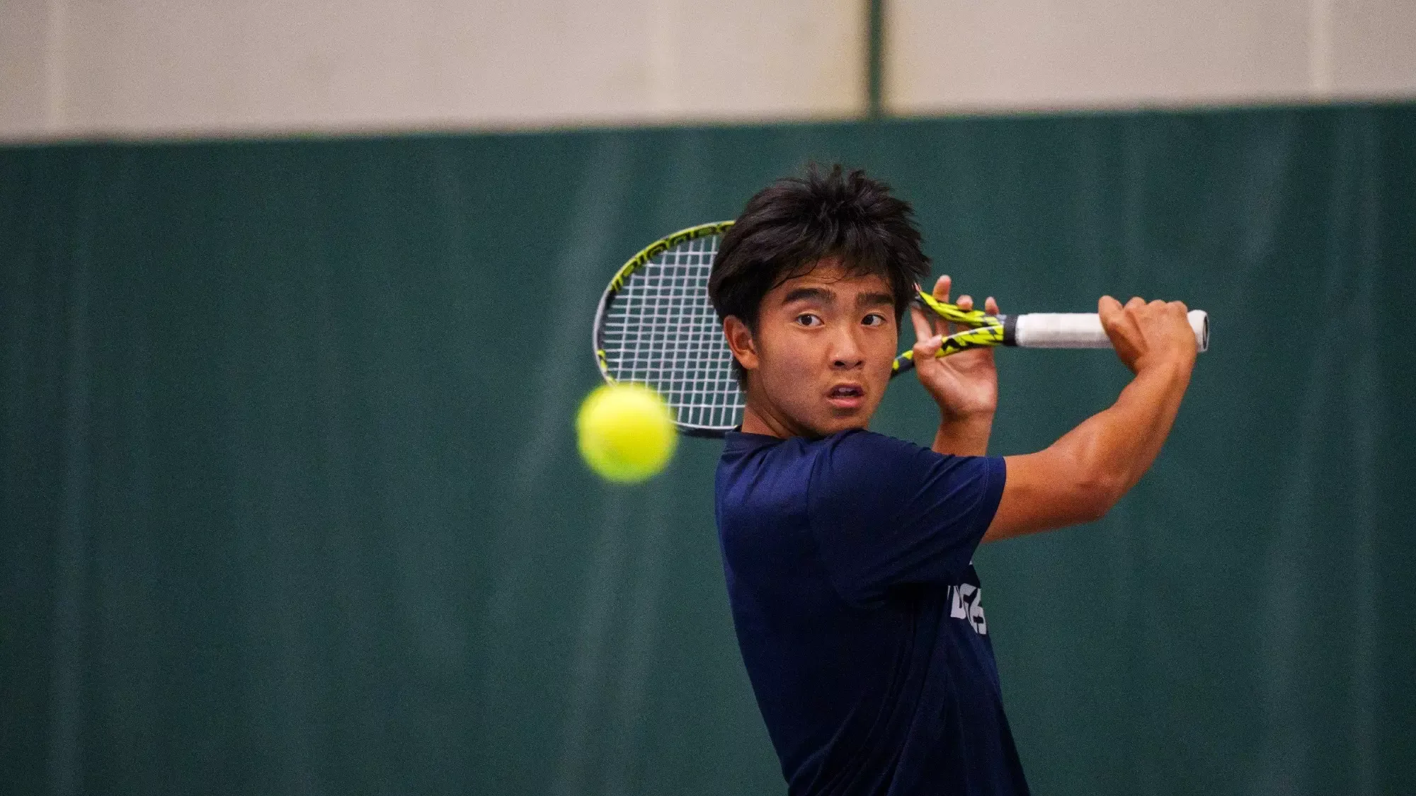 Aidan Wang-Fan prepares to hit a backhand during a tennis match