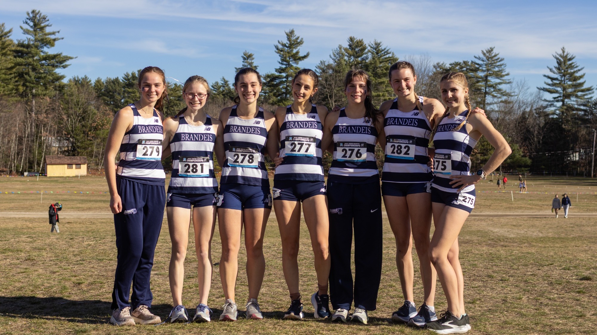 The seven Brandeis Women's Cross Country runners that helped the Judges finish 3rd in the East Region, posing in a field
