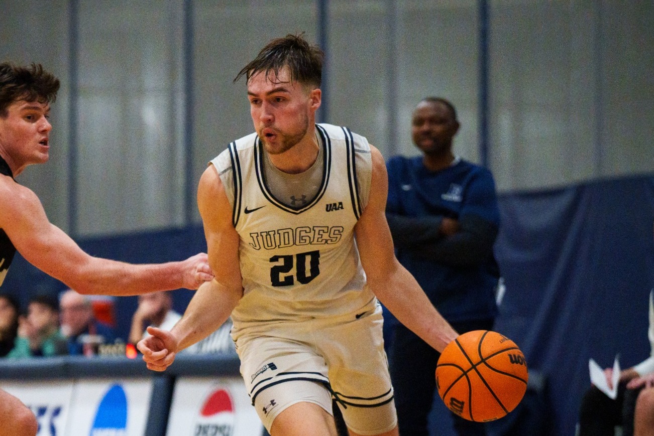 Photo of Brandeis player Elias Rodl dribbling a basketball