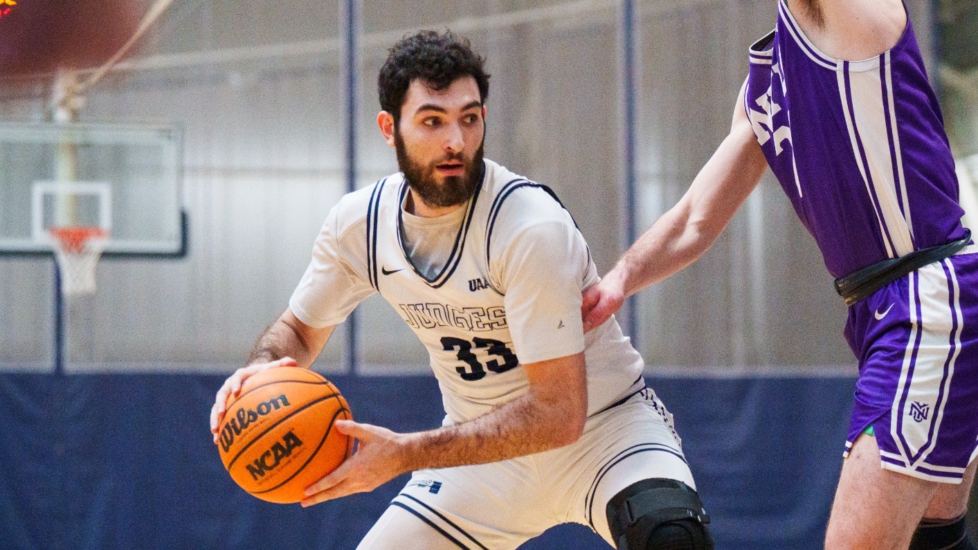 Aedan Using holds the basketball while a defender guards him