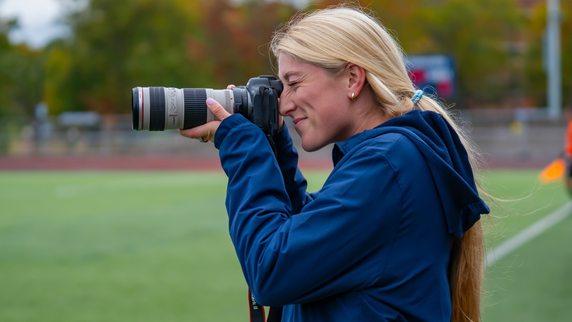 Side profile of Julia Berg looking through a camera at the soccer field