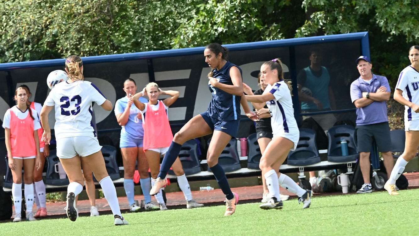 Zareena Mann between two defenders during a soccer match