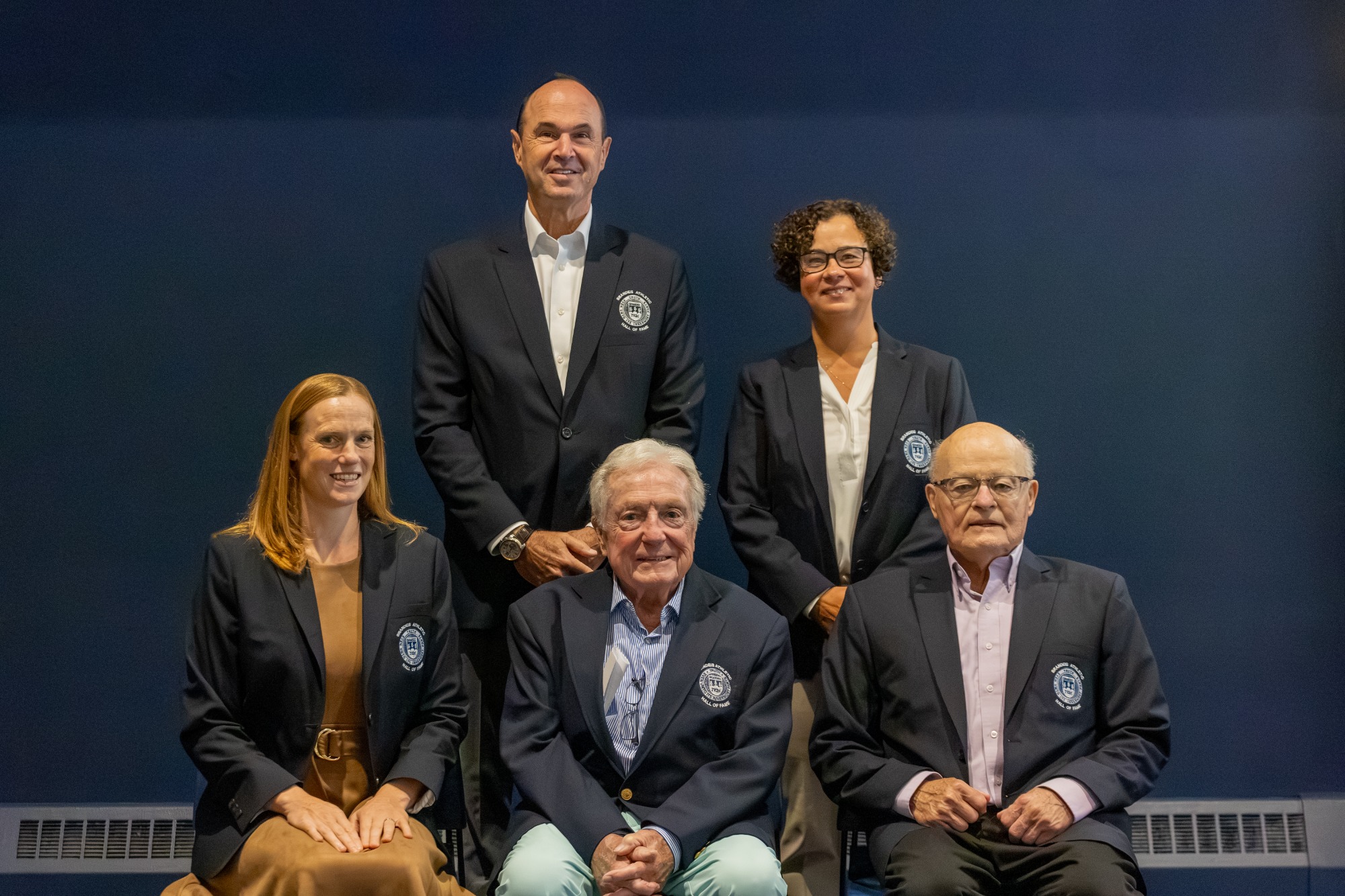 The Brandeis Hall of Fame Class of 2026 
Front, left to right - Caitlin Malloy '03, Coach Tom Foley , Dave Walker '60
Back, left to right - Elliot Schwartz '82, Theresa Gomes '97