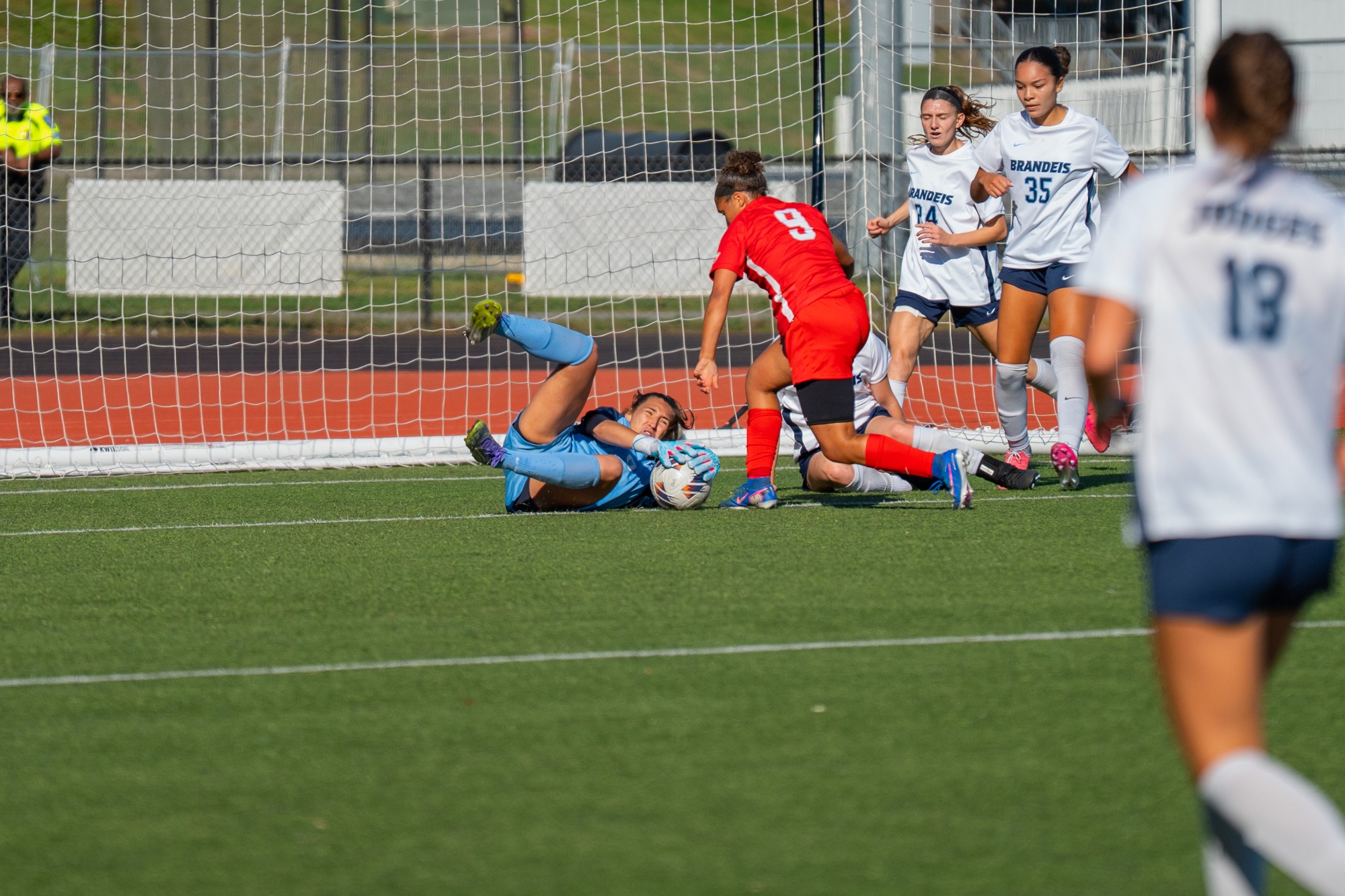 Brandeis goalkeeper Amaya Logan in her blue jersey makes one of 10 saves for the Brandeis women against WashU