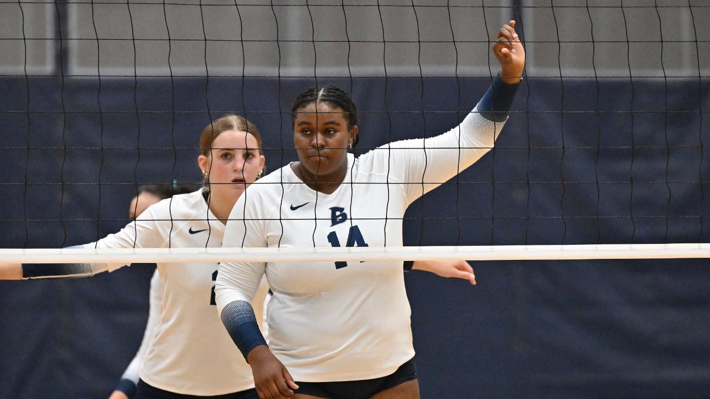 Kennedy Lilly holds up her hands calling a play as she awaits a serve during a volleyball match