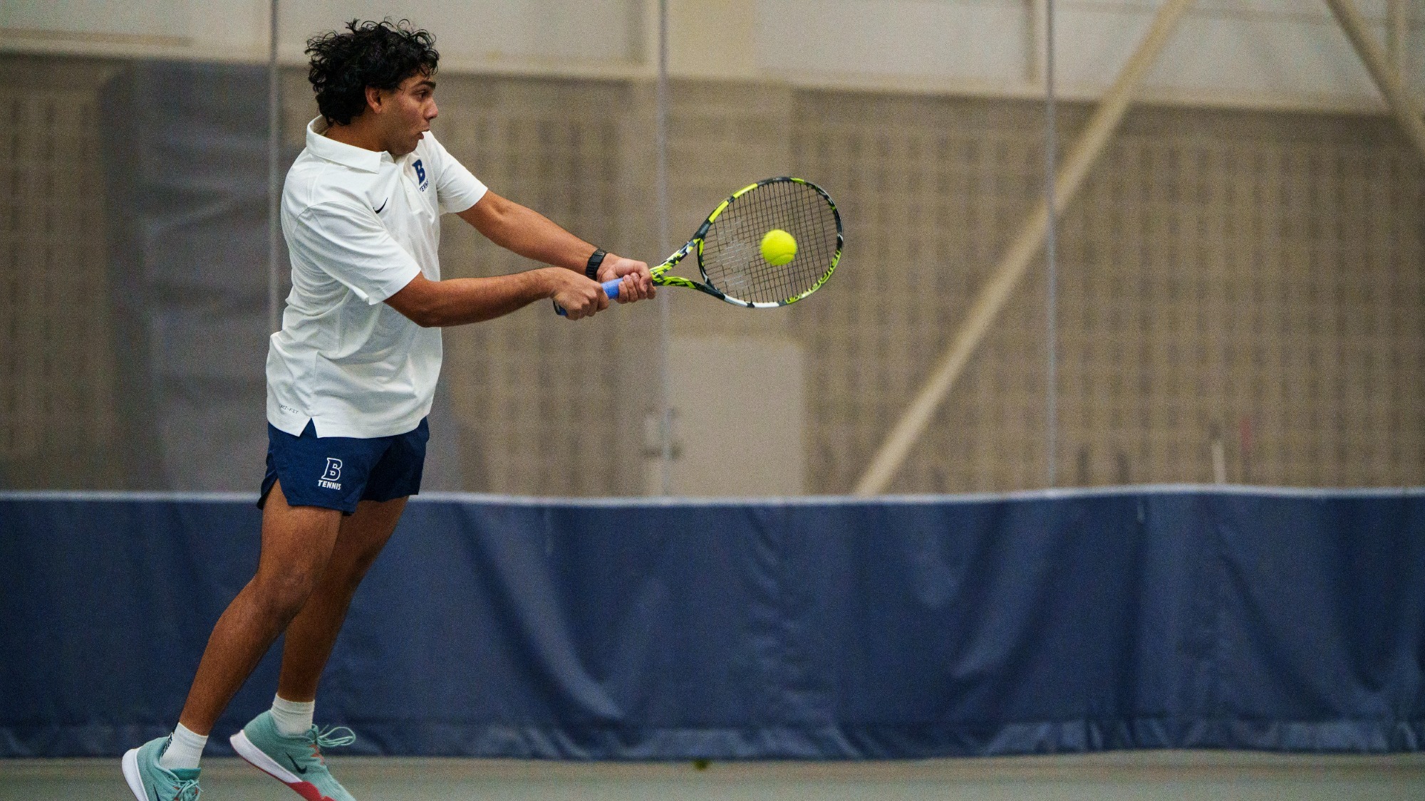 Muaz Malik hits a two-handed return during a tennis match