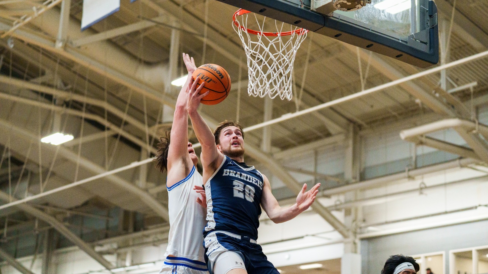 Elias Rodl attacks the basket with a defender trying to block him from behind during a basketball game