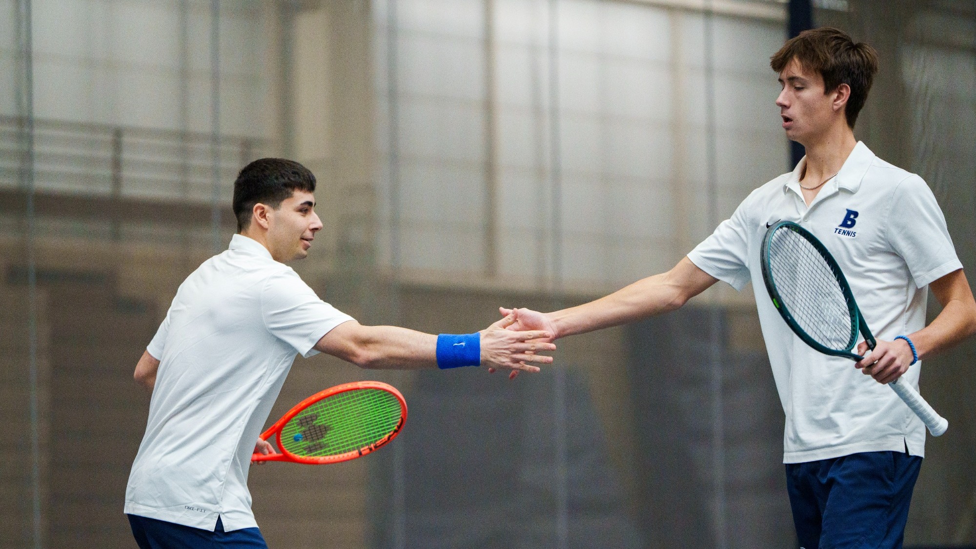 Daniel Shemesh and Oliver Lorenz give low-fives between points of a tennis match