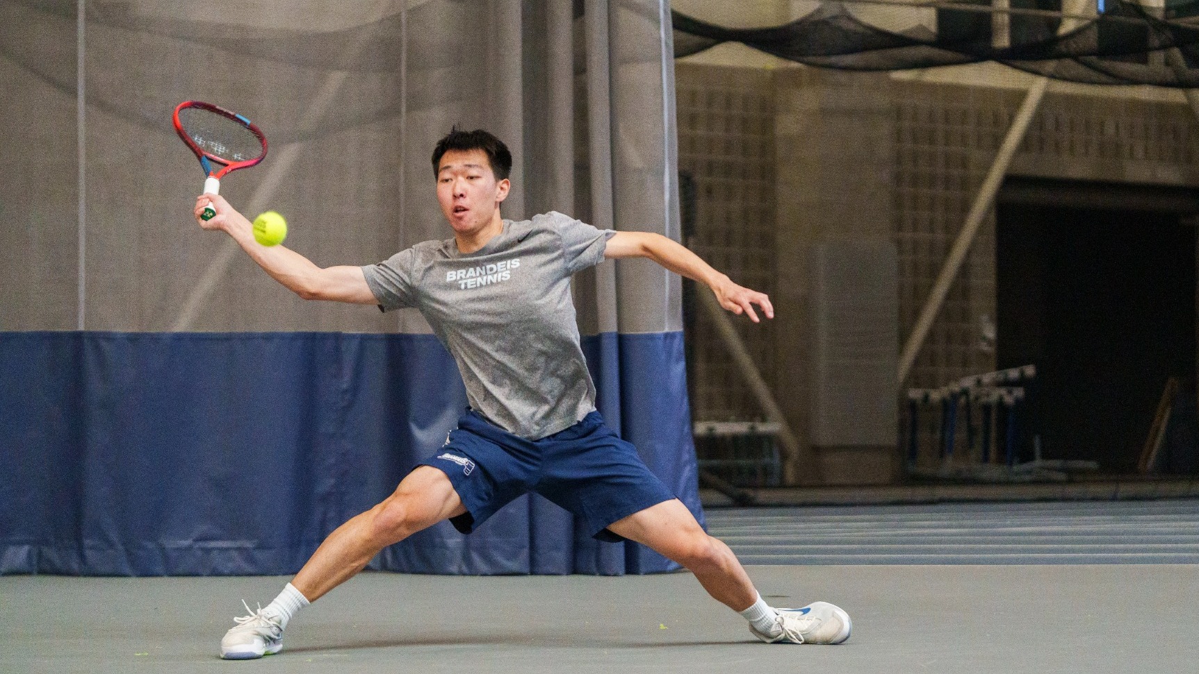 Huasen Dong stretches for a return during a tennis match