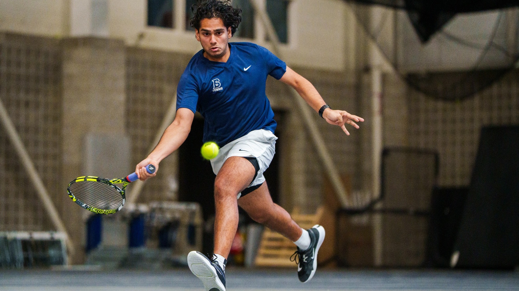 Muaz Malik chases down a tennis ball during a match