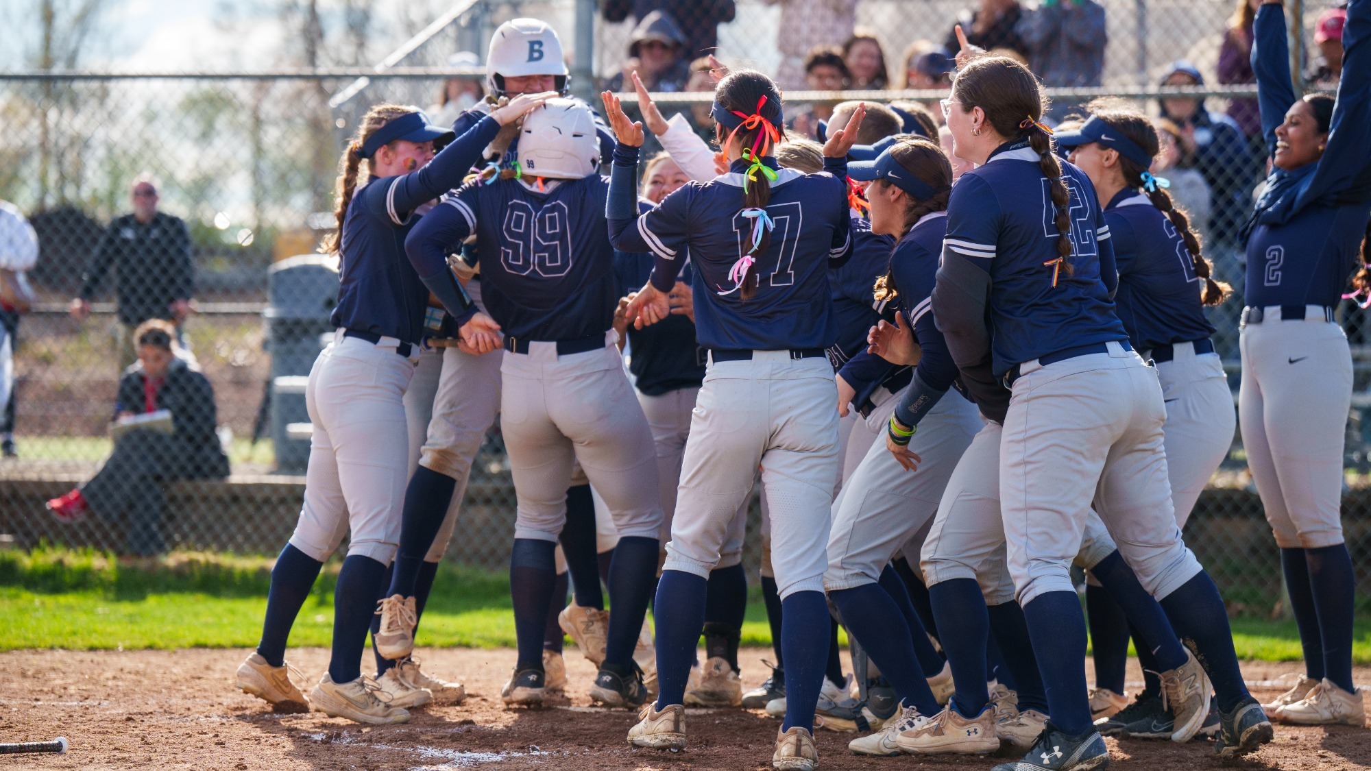 Brandeis softball celebrates a home run by #99 Jordan Wallace against WashU