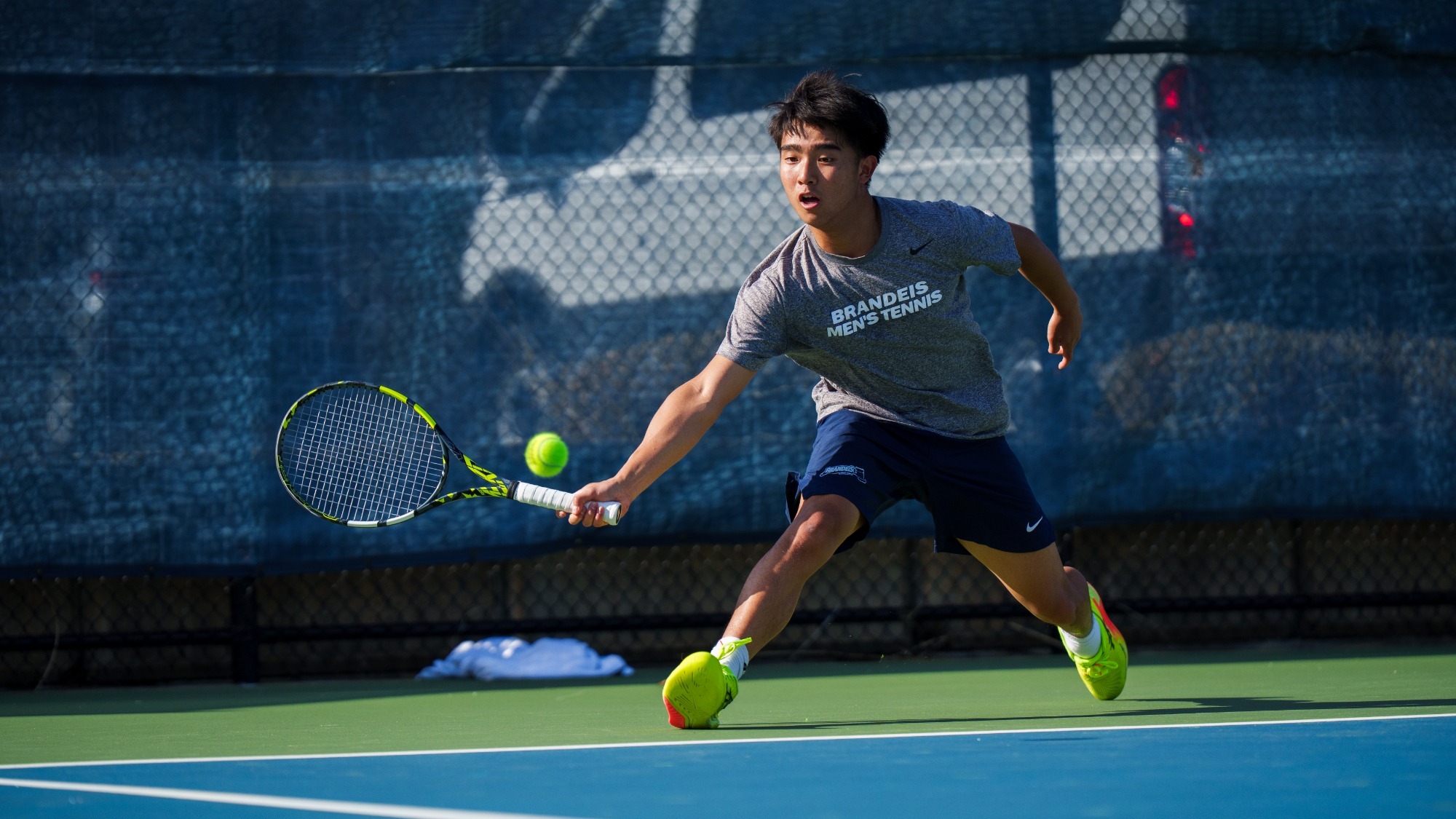 Aidan Wang-Fan goes for a forehand return during a tennis match