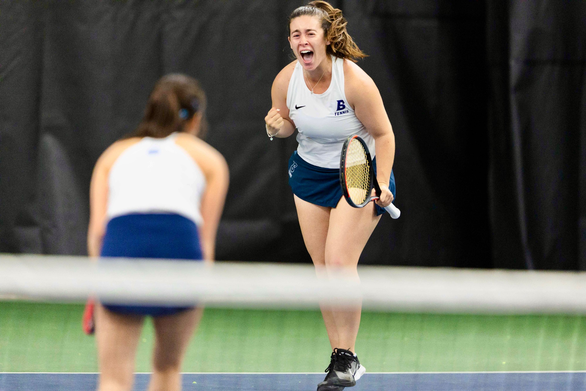 Rebecca pumps her fist and shouts at Mandy after the Judges clinch their opening round win at the NCAA Division III Doubles Tournament