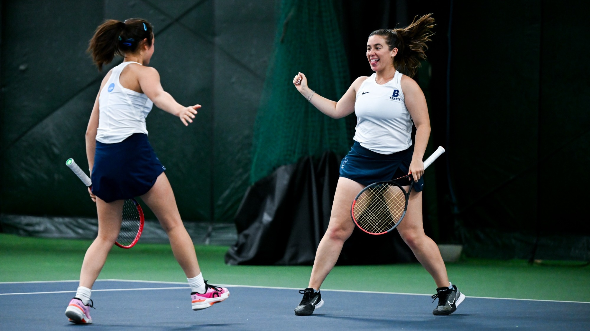 Rebecca Suarez and Mandy Reyes high-five after winning a point in their NCAA Division III Doubles Tournament quarterfinal
