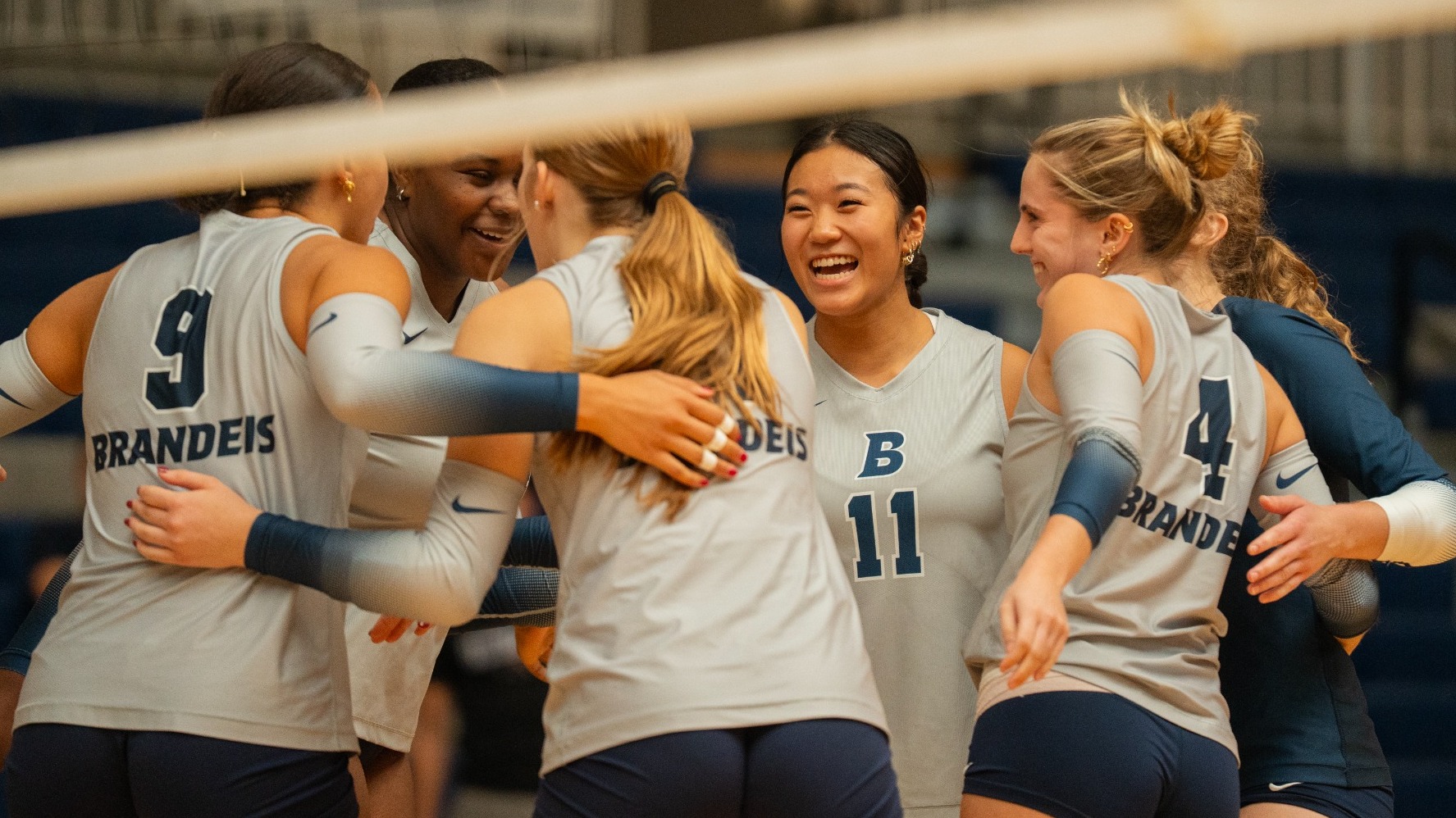 Volleyball team is all smiles in a huddle after winning a point