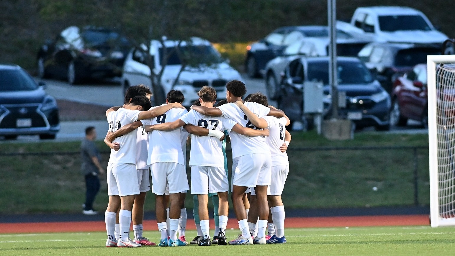 Brandeis men's soccer players huddle before a game