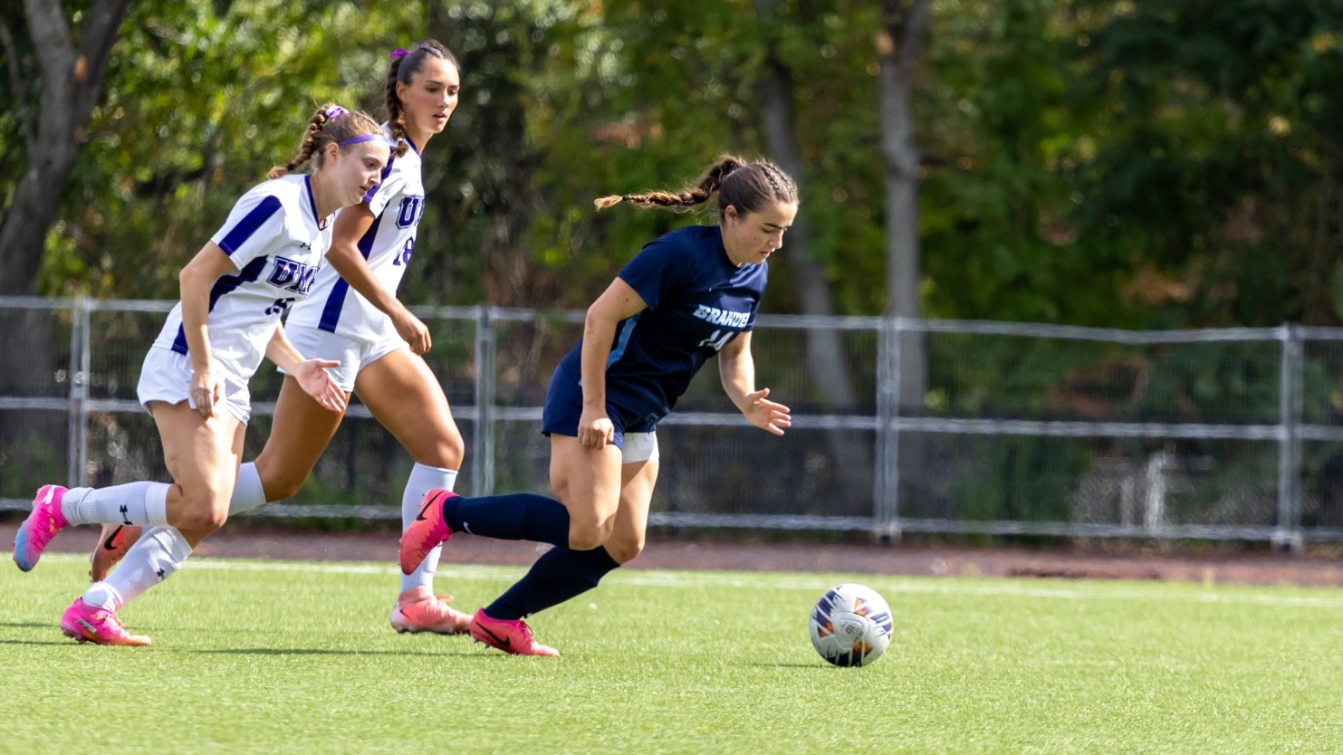 Reilly Hickey dribbles past a pair of defenders on the soccer field