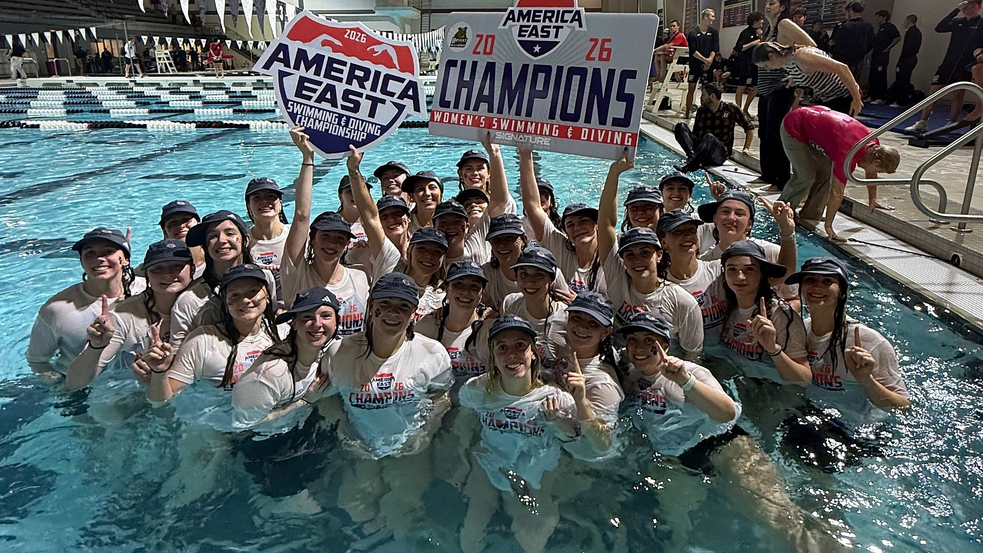 Team picture of women's swimming and diving team celebrating title in the pool