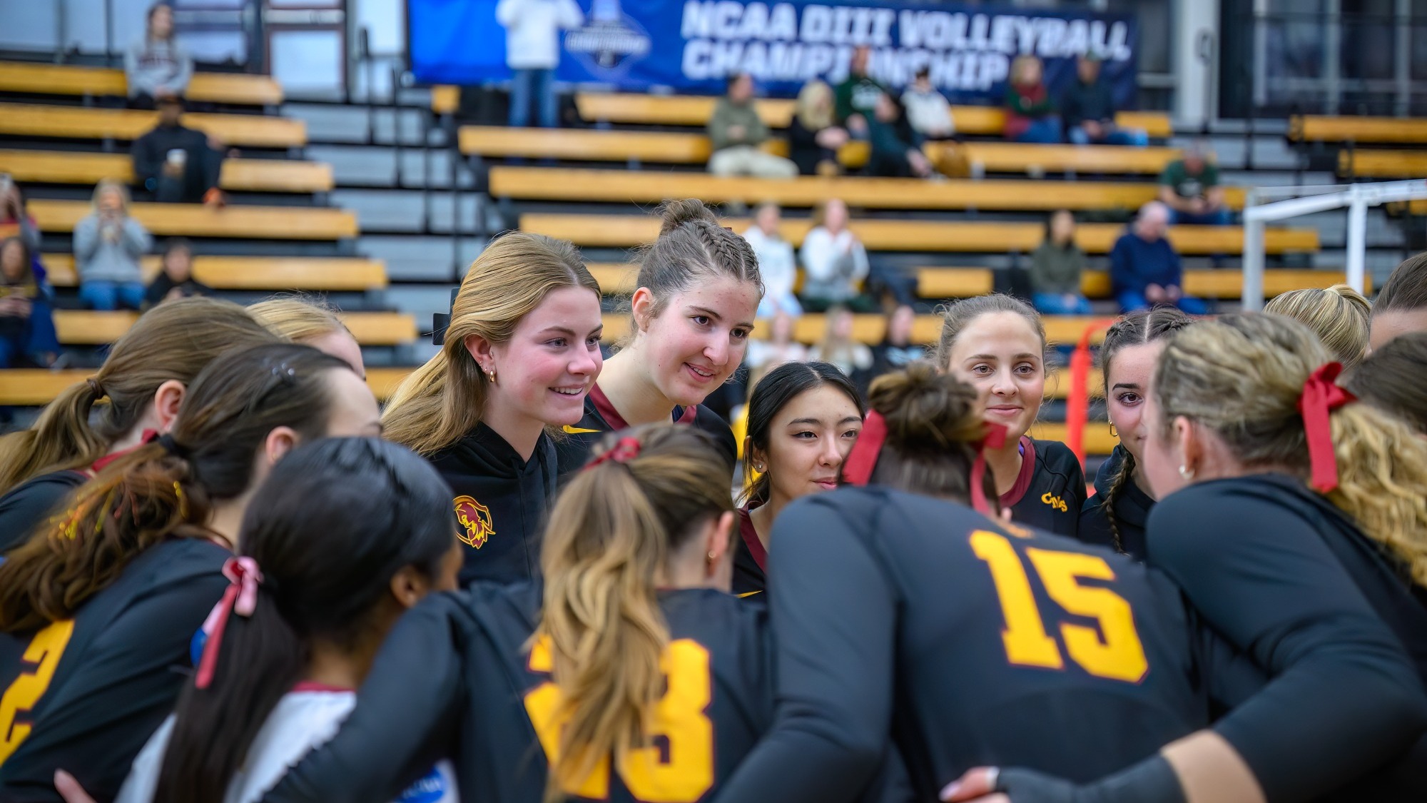 CMS Volleyball Team huddle underneath an NCAA banner