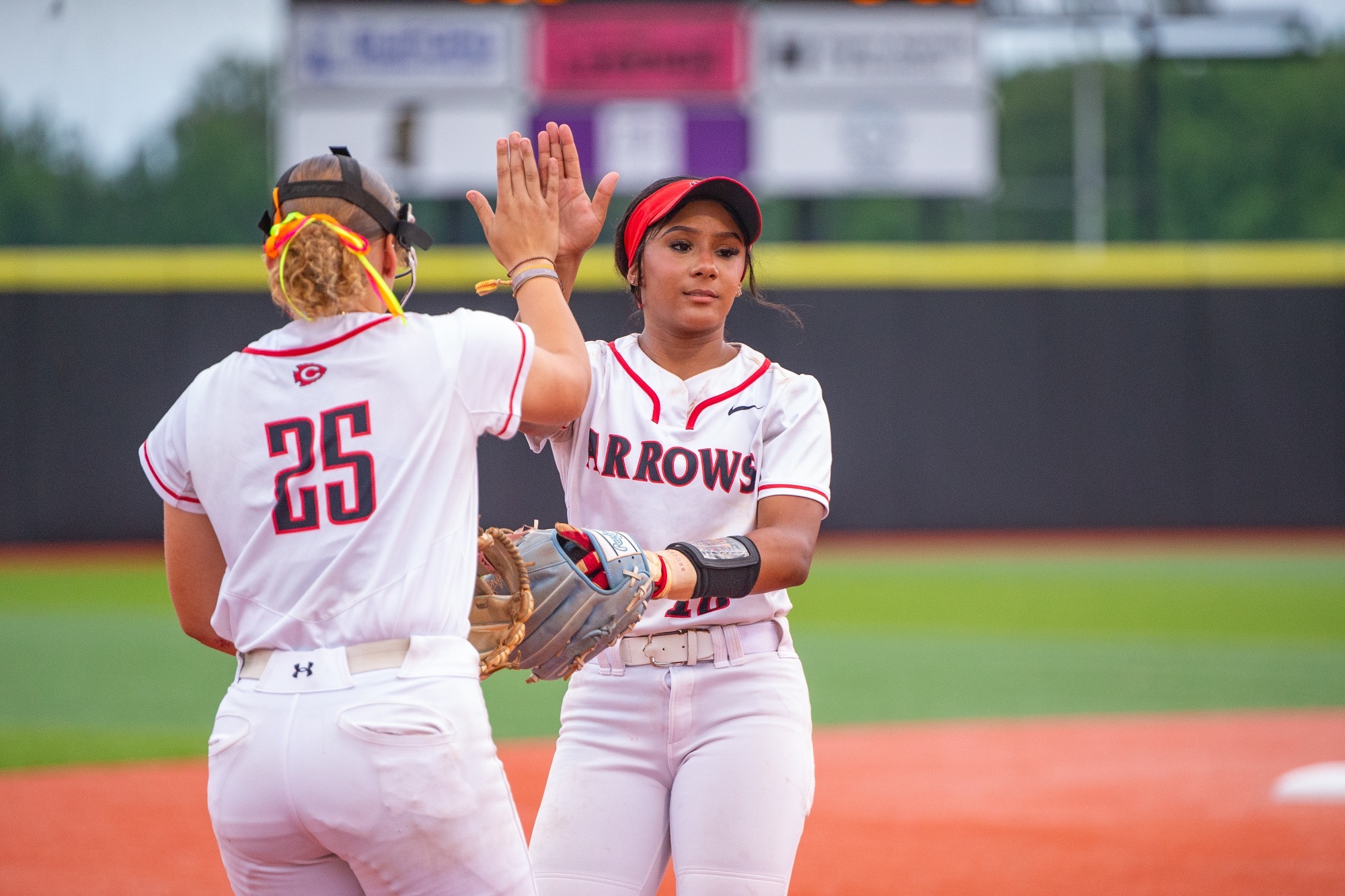 Two Lady Arrows celebrate a successful inning of defense.