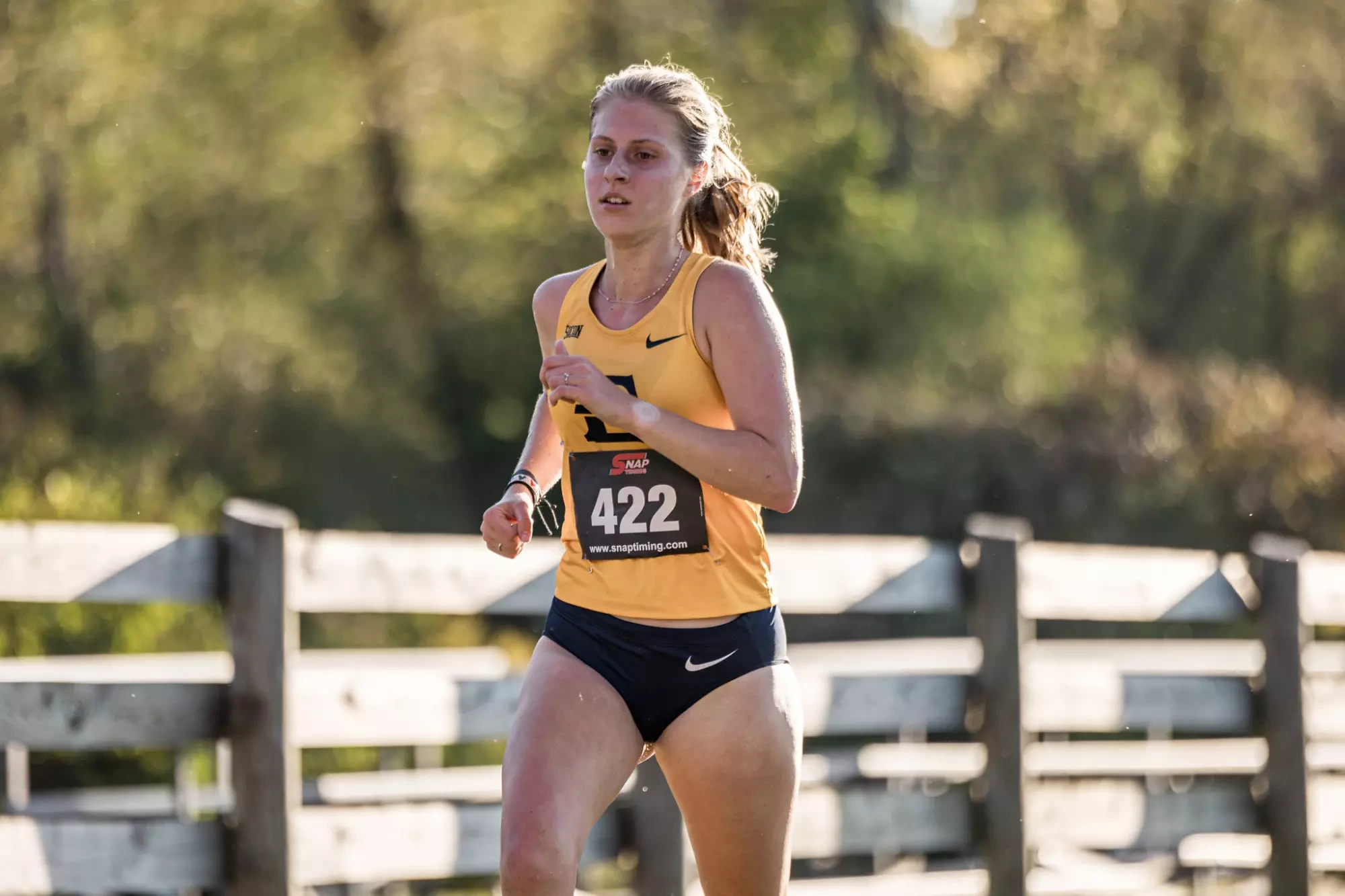 Eliza Everett runs along a fence row during a cross country face in Blacksburg, Virginia.