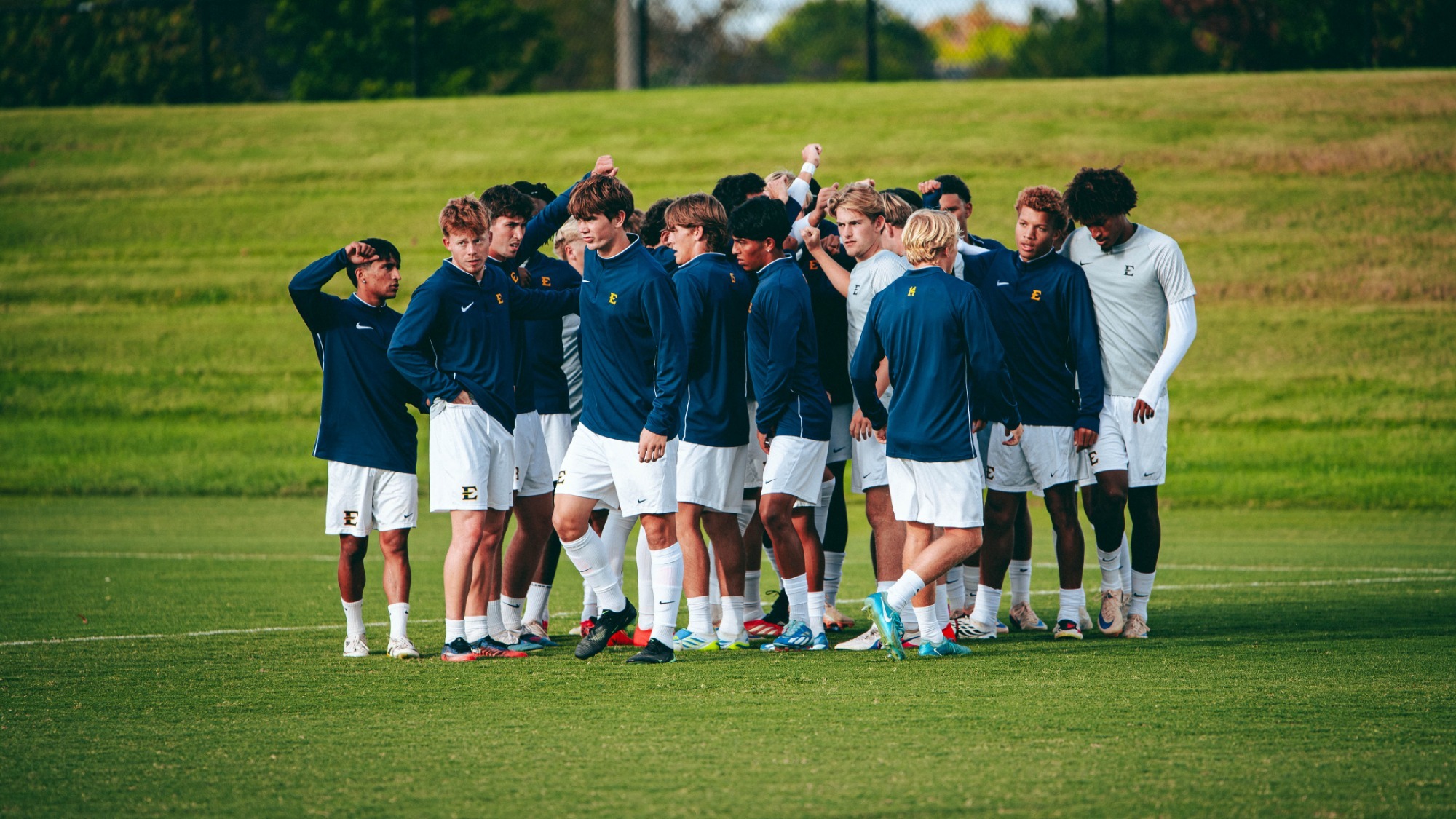 The ETSU men's soccer team huddles in their navy blue warm-up kits before a match against Liberty.