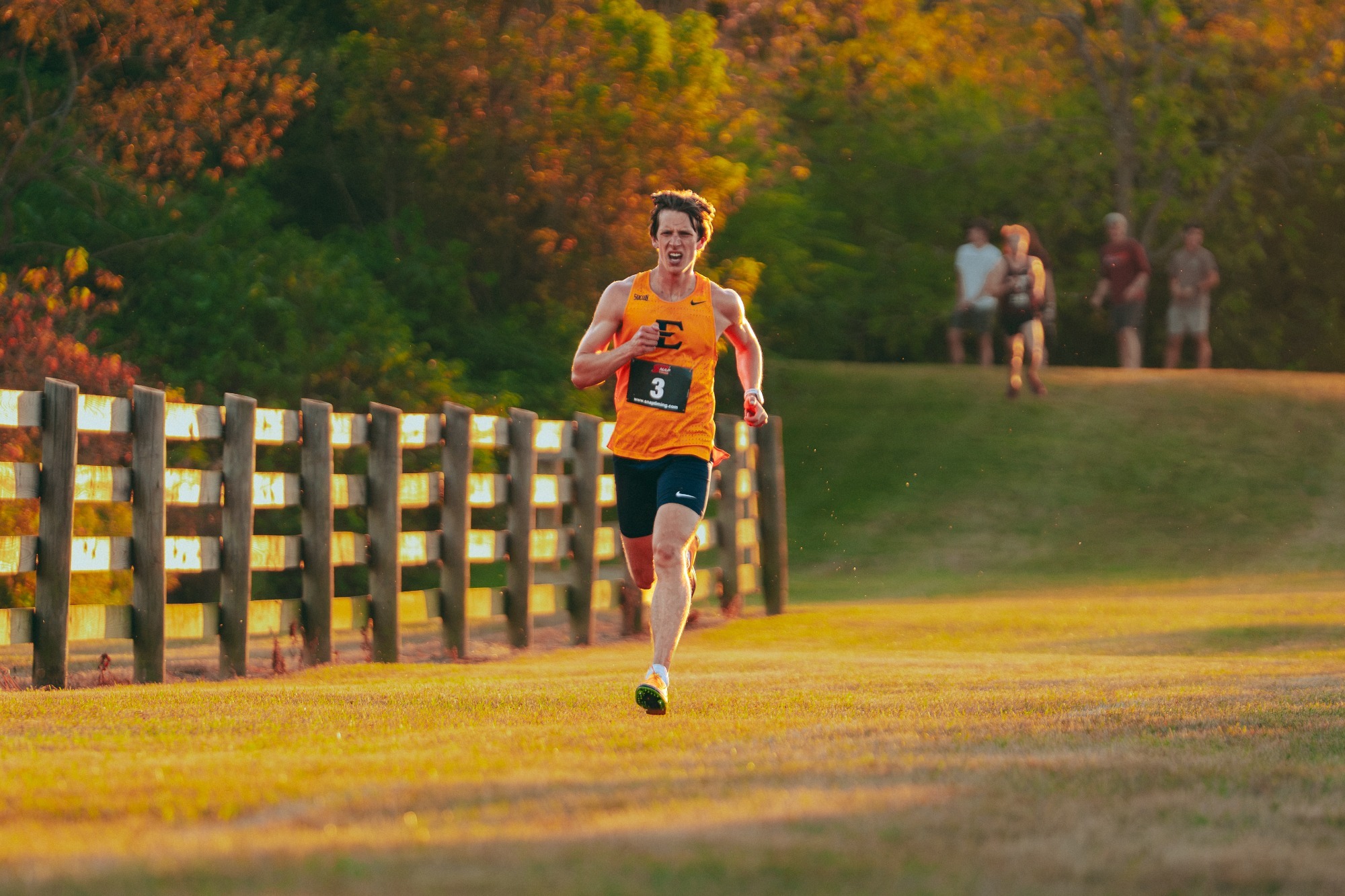 Garrett Hawkins runs along a fencerow during a cross country race in Blacksburg, Virginia.