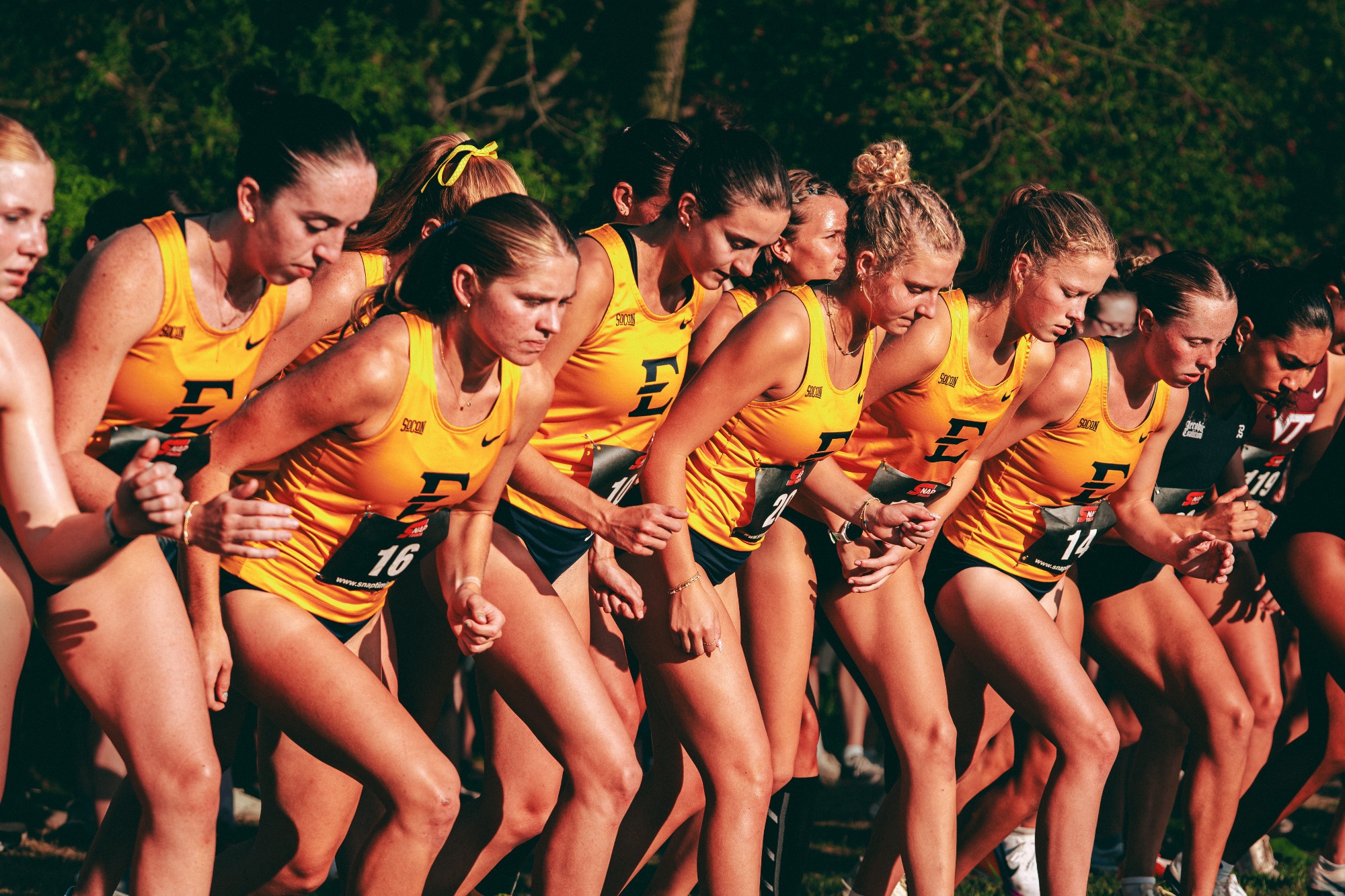 The ETSU women's cross country team leans onto the starting line moments before the start of a race in Blacksburg, Virginia.