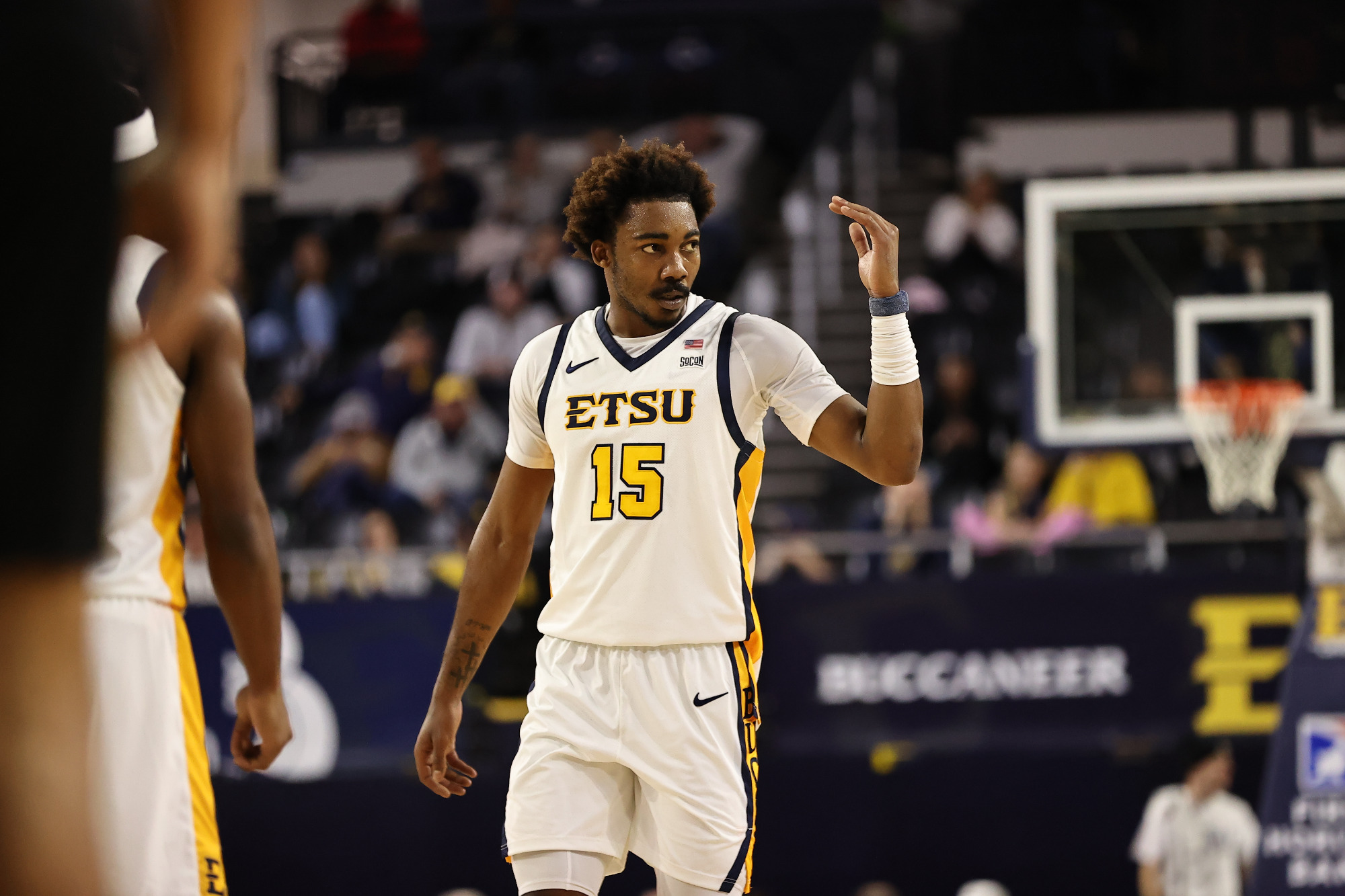 Cam Morris, wearing ETSU's white home jersey, raises his left hand as if to gesture for the opponent to 