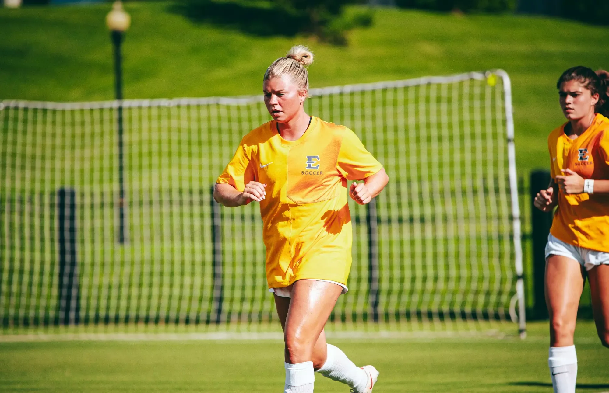 Ella Parker jogs along the sideline in her gold warm-up jersey before a soccer match.