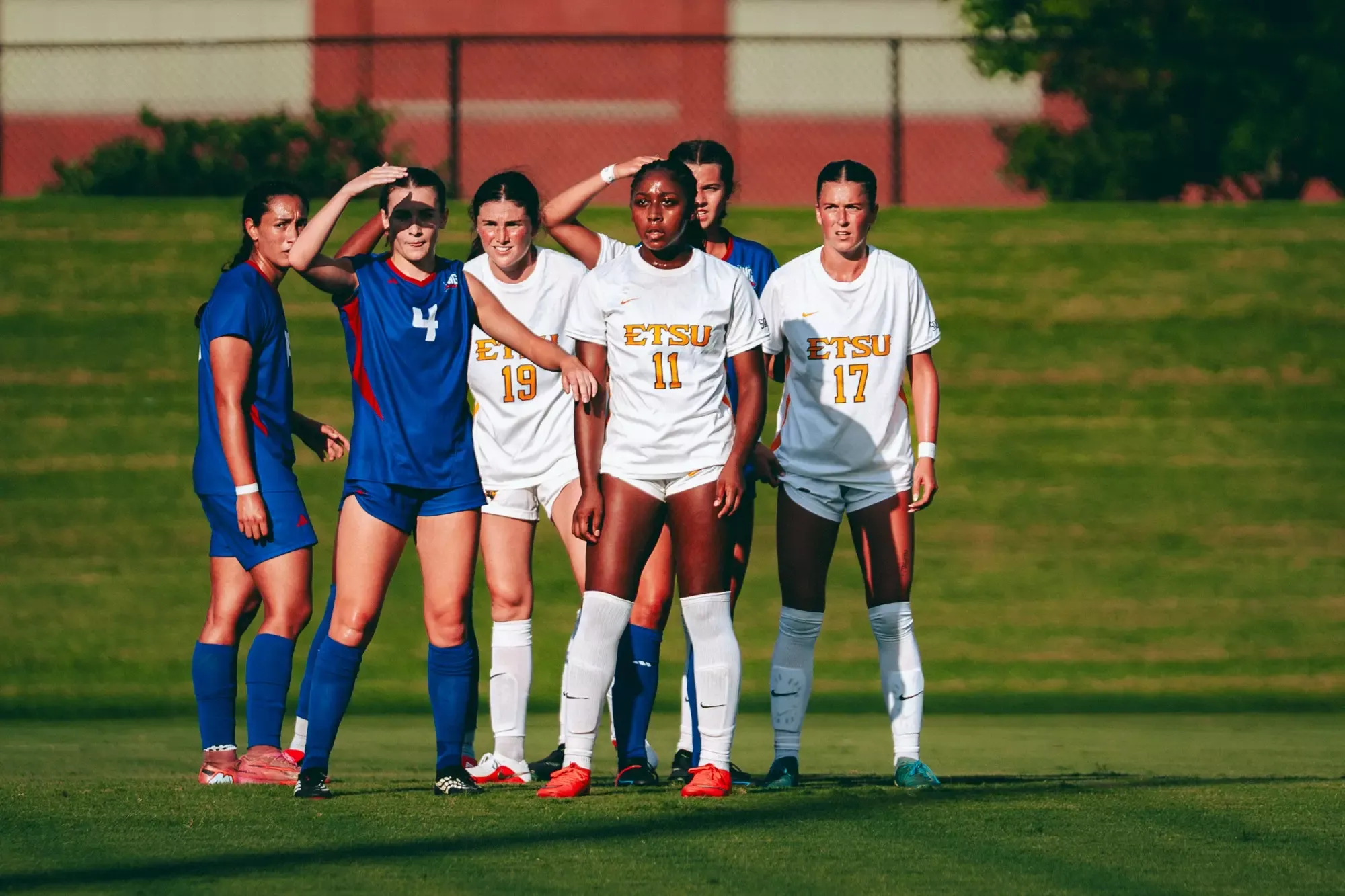Jada Cooper stands in front of her teammates in the setting sun during a lull in play in a soccer match.
