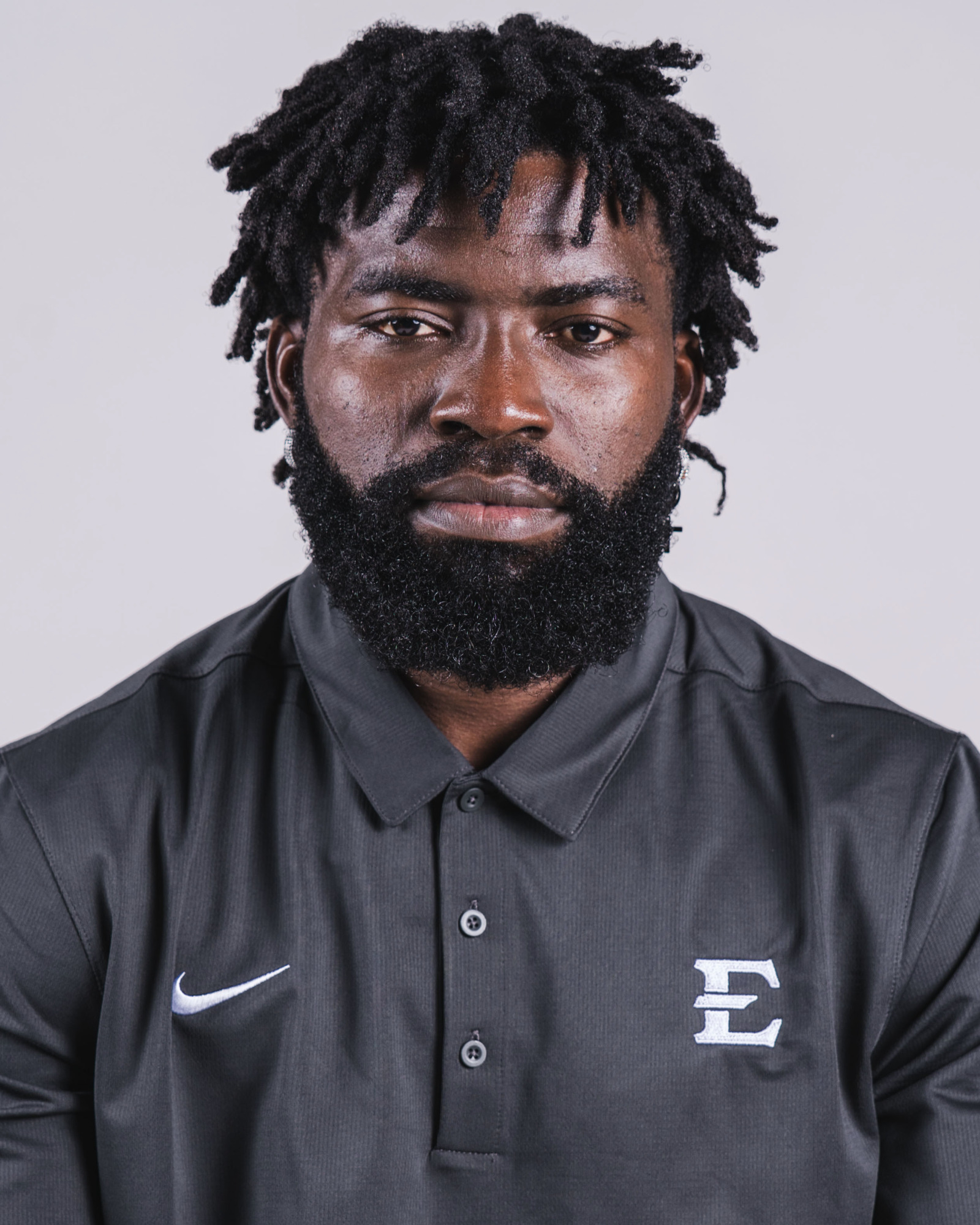 A headshot of Serge Gomis in his gray coach's polo.