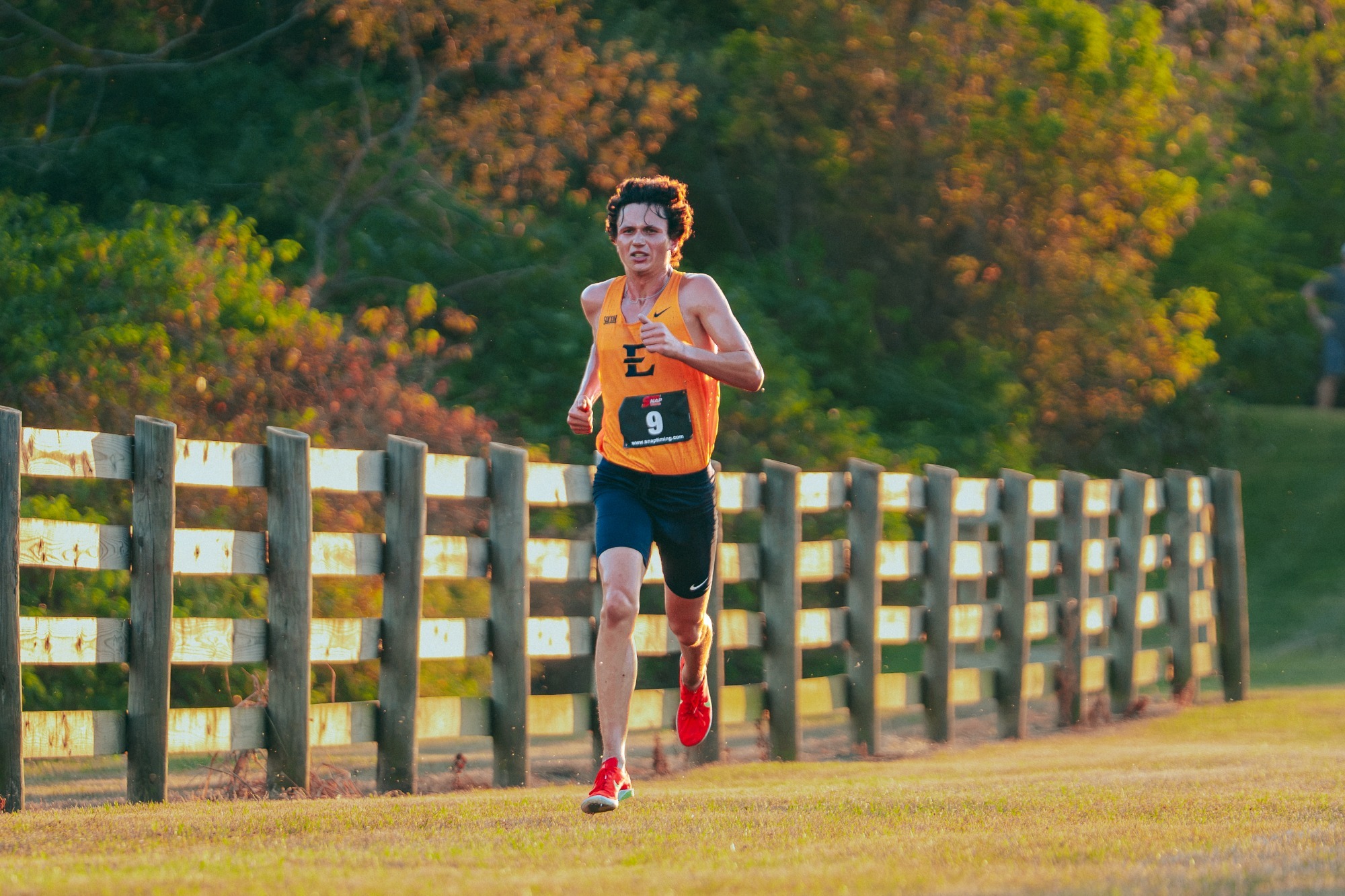 Hayden Waleski runs along a fence row with the setting sun at his back during a cross country race in Blacksburg, Virginia.