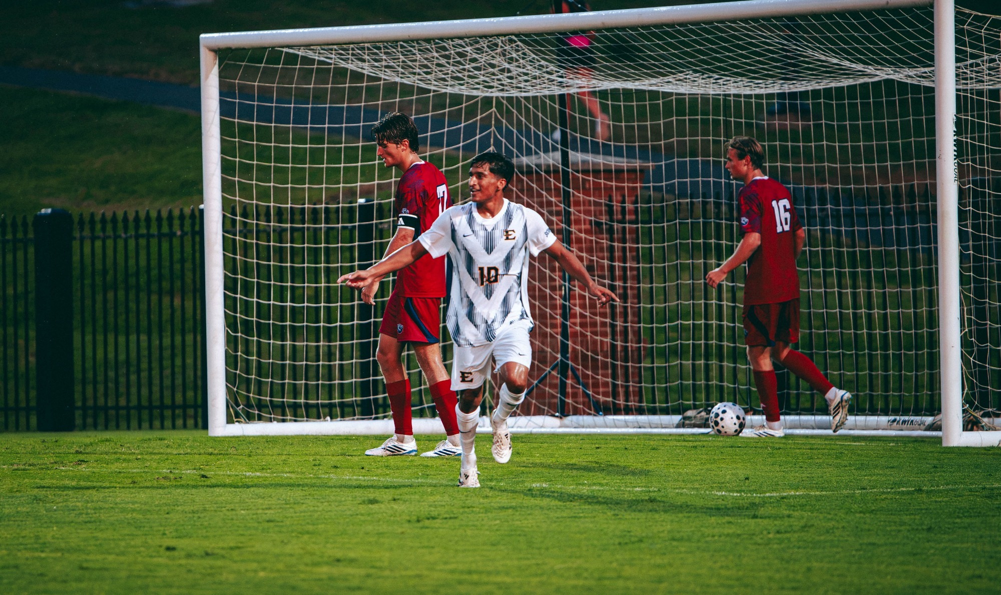 Jaime Carrillo celebrates scoring a goal against Belmont during a soccer match as Bruins players extricate the ball from their own net.