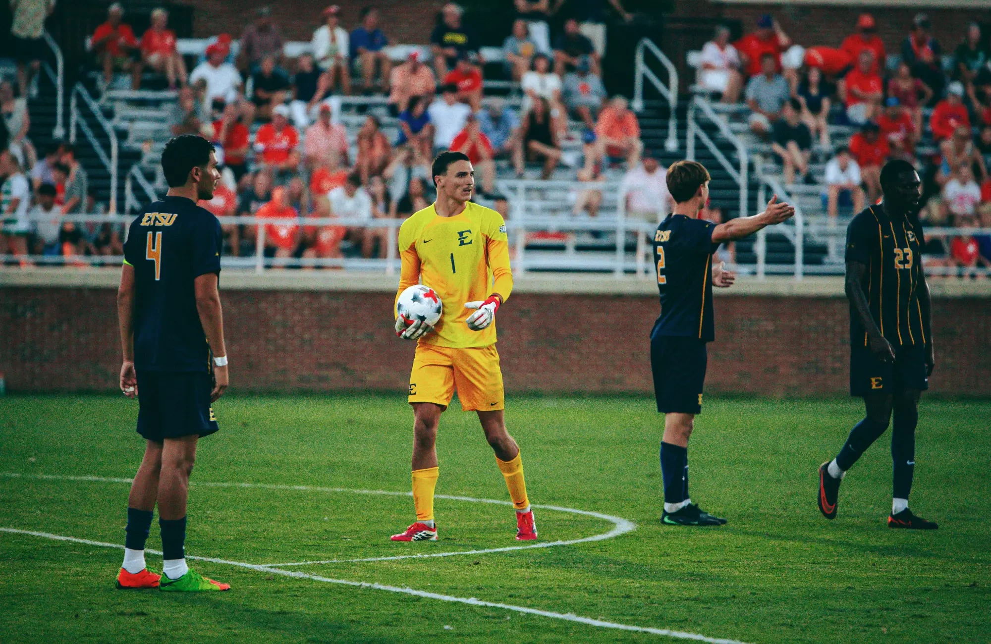 Noé Delmotte holds the ball during a stoppage in play in a soccer match at Clemson. Three ETSU defenders surround their goalkeeper.