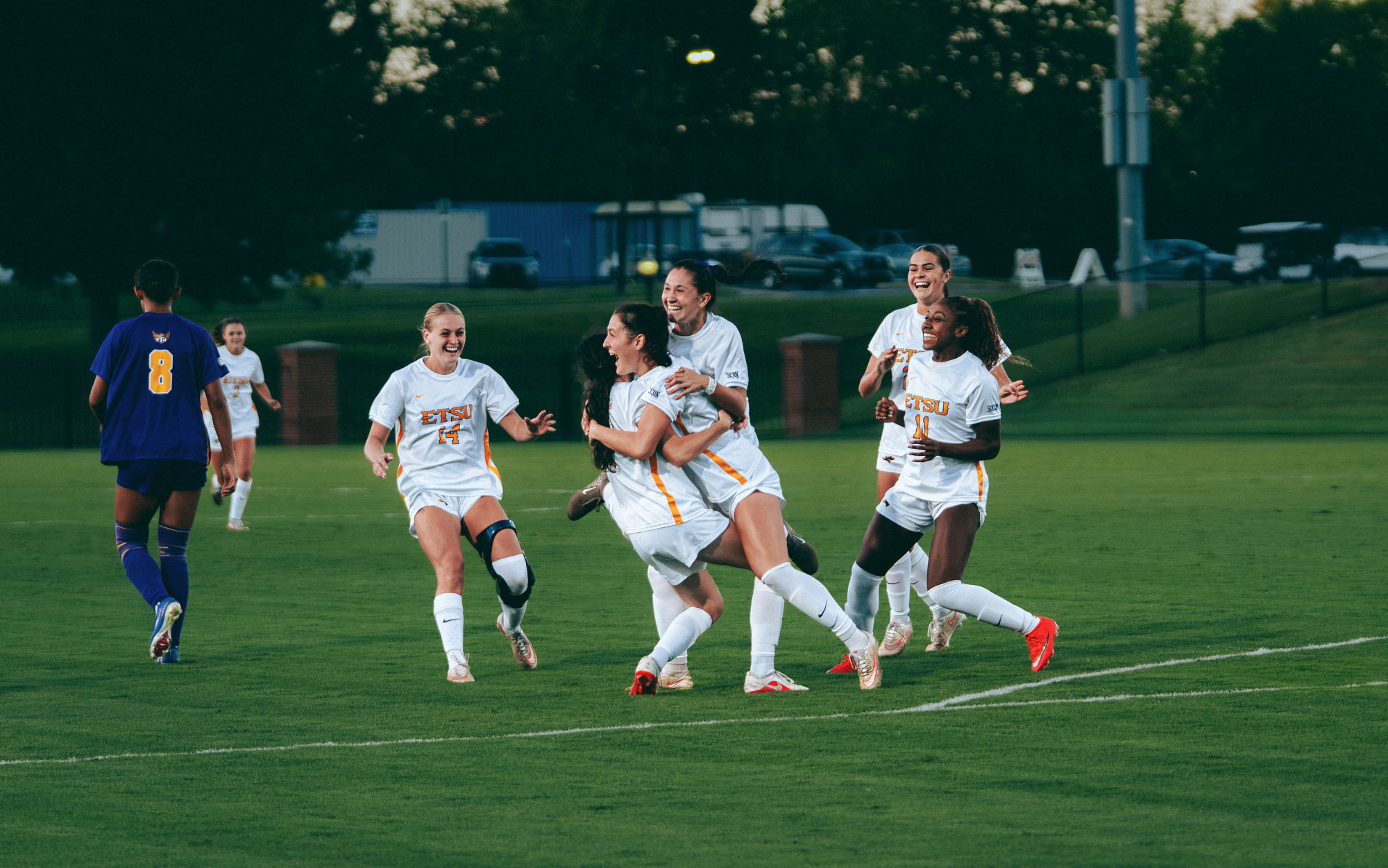 Natalie Capannelli tackles Reagan Fitzgerald in celebration moments after Capannelli's first goal in nearly two years. Other teammates close in around them to celebrate.