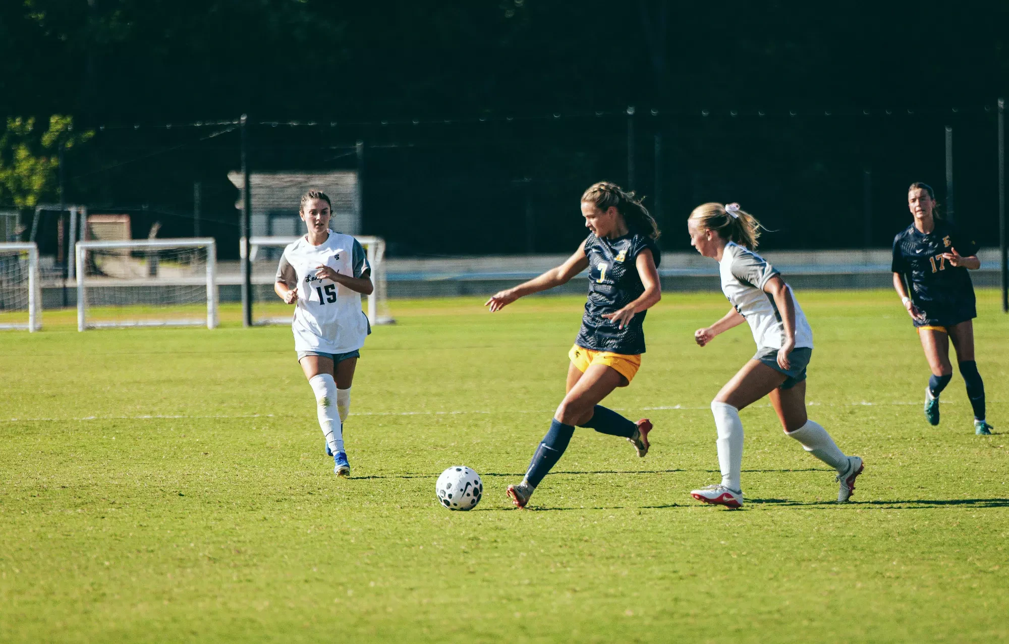 McKlain Jones lines up an outlet pass with her right foot while being pressured by a defender during a soccer match at Longwood.
