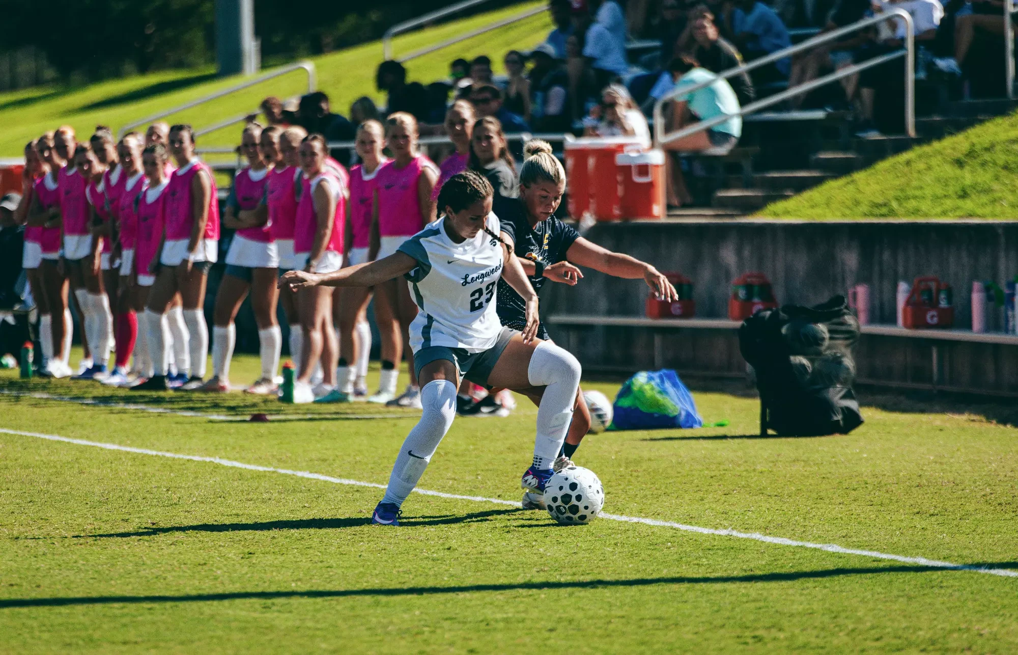 Ella Parker fights a Longwood player for the ball along the touch line during a soccer match.