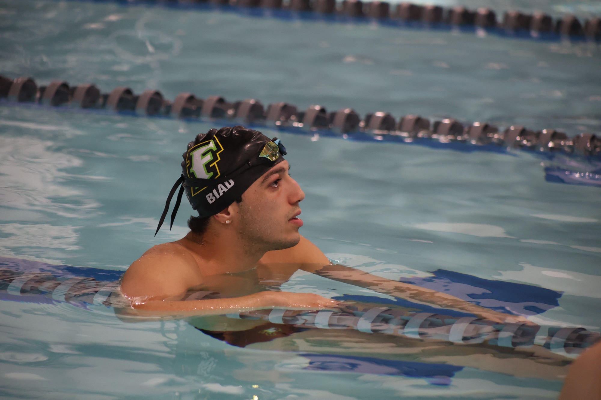 Malik Biad rests on a lane divider with his goggles up after a race.