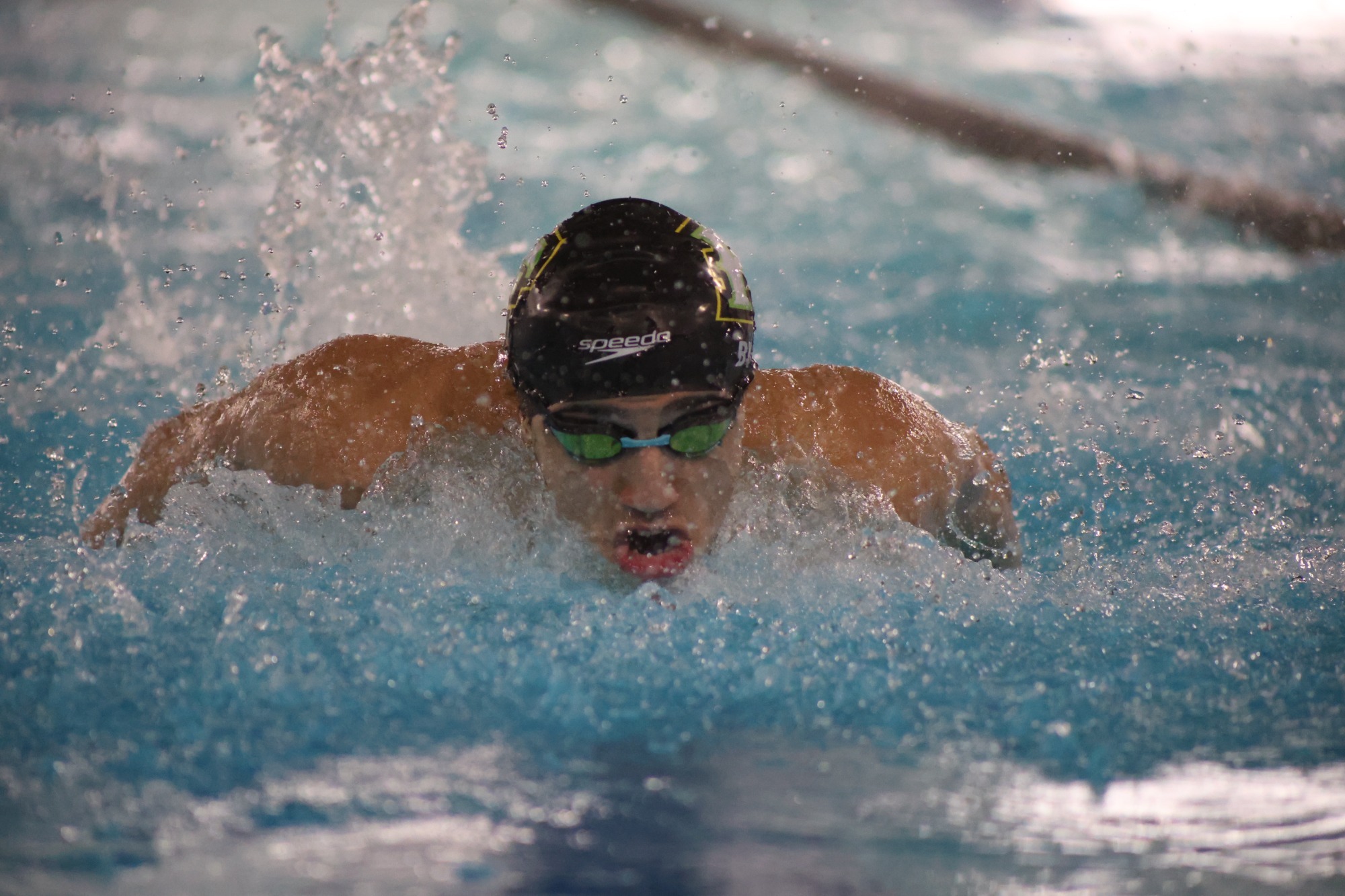 Malik Biad breaches the water mid butterfly stroke