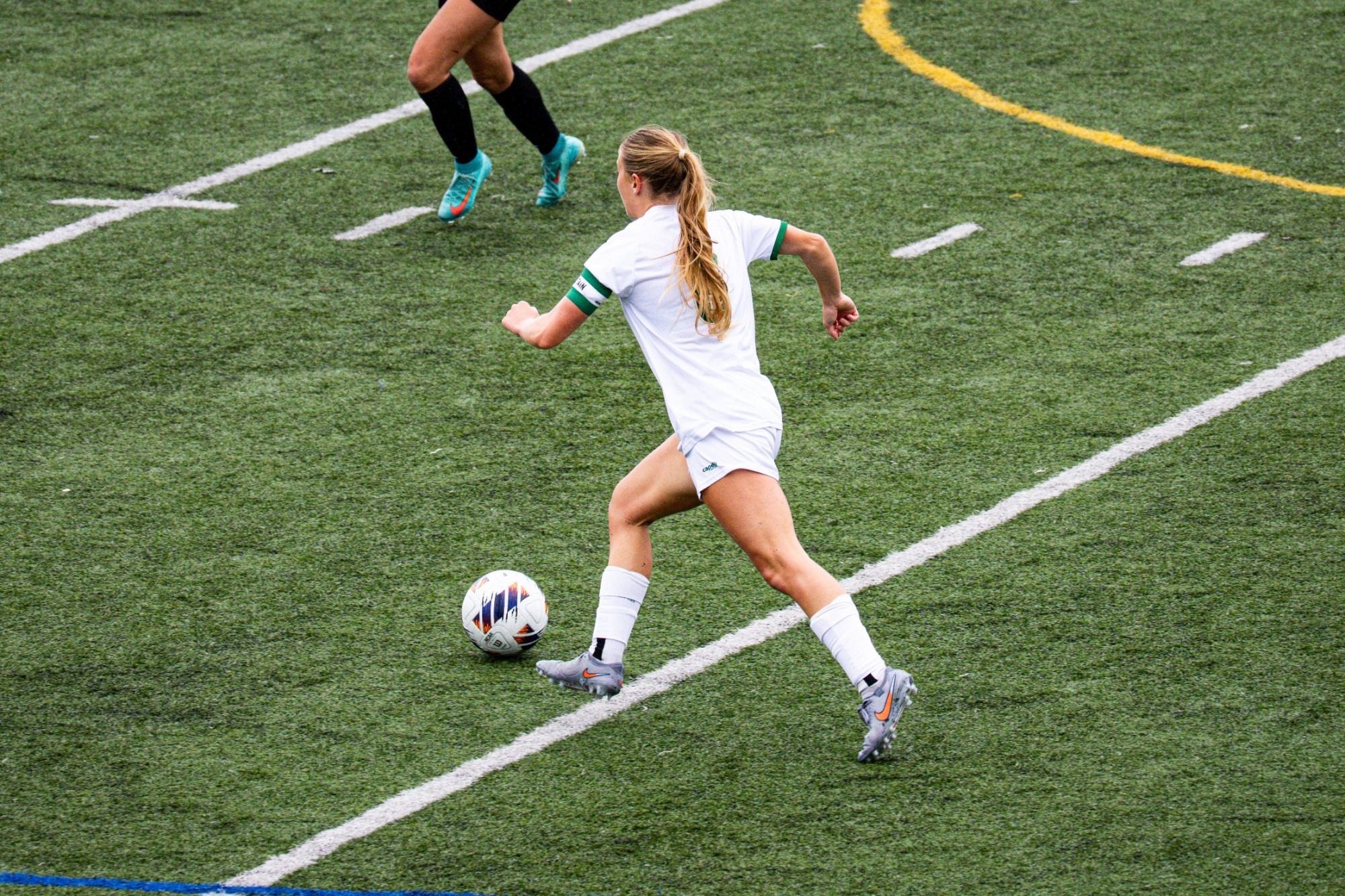 April Fischer dribbling up field with soccer ball