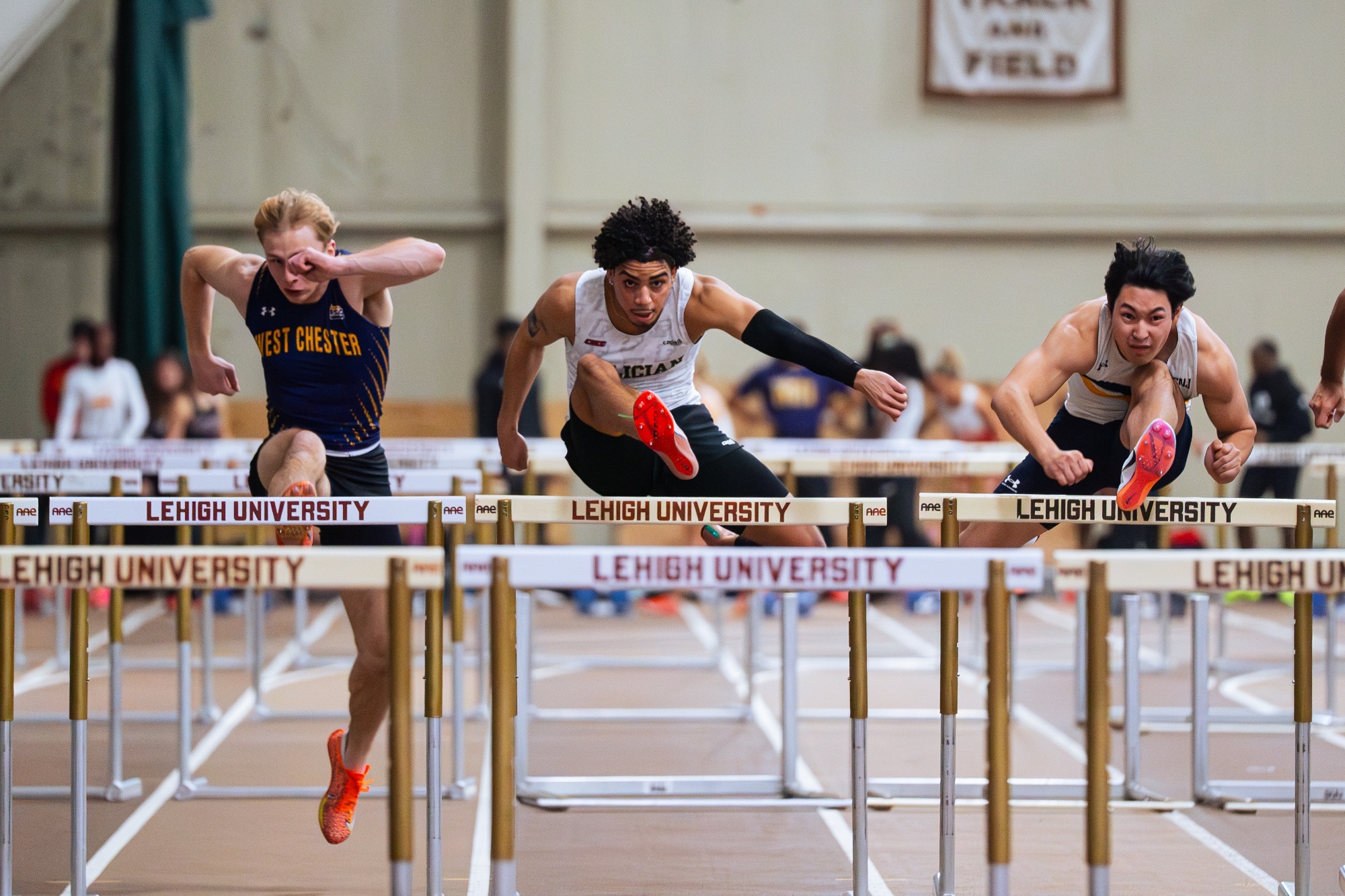 Men's Indoor Track and Field jumping over hurdles